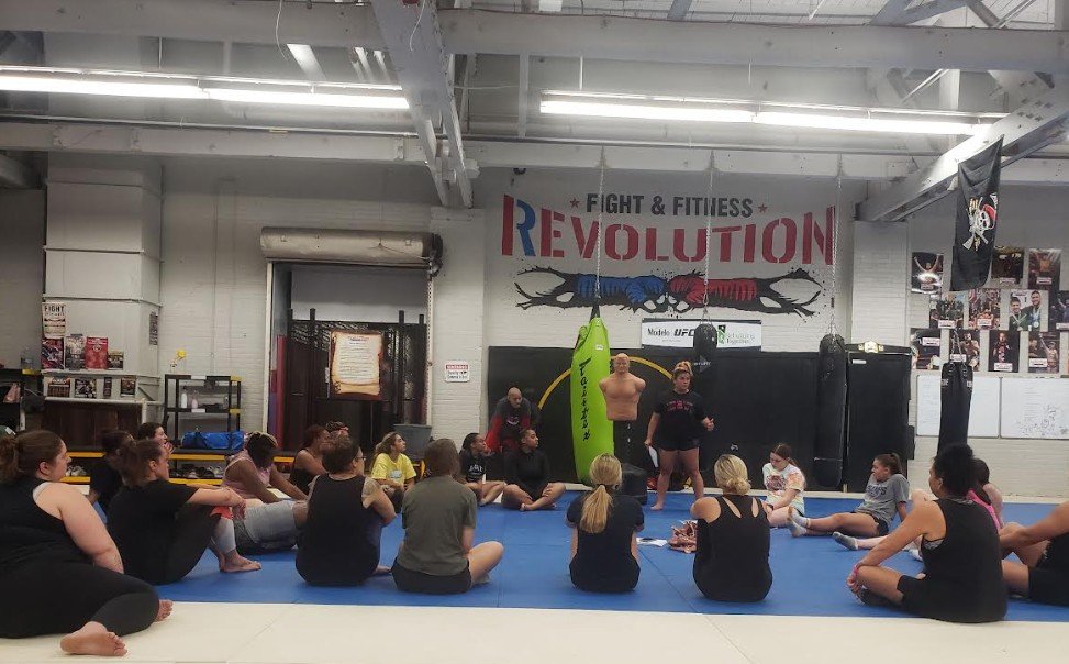 Women's empowerment expert Dr. Alice Atalanta pictured at Revolution Fight & Fitness in Euclid Ohio after a women's empowerment boxing and self-defense seminar with a group of women feeling strong and empowered
