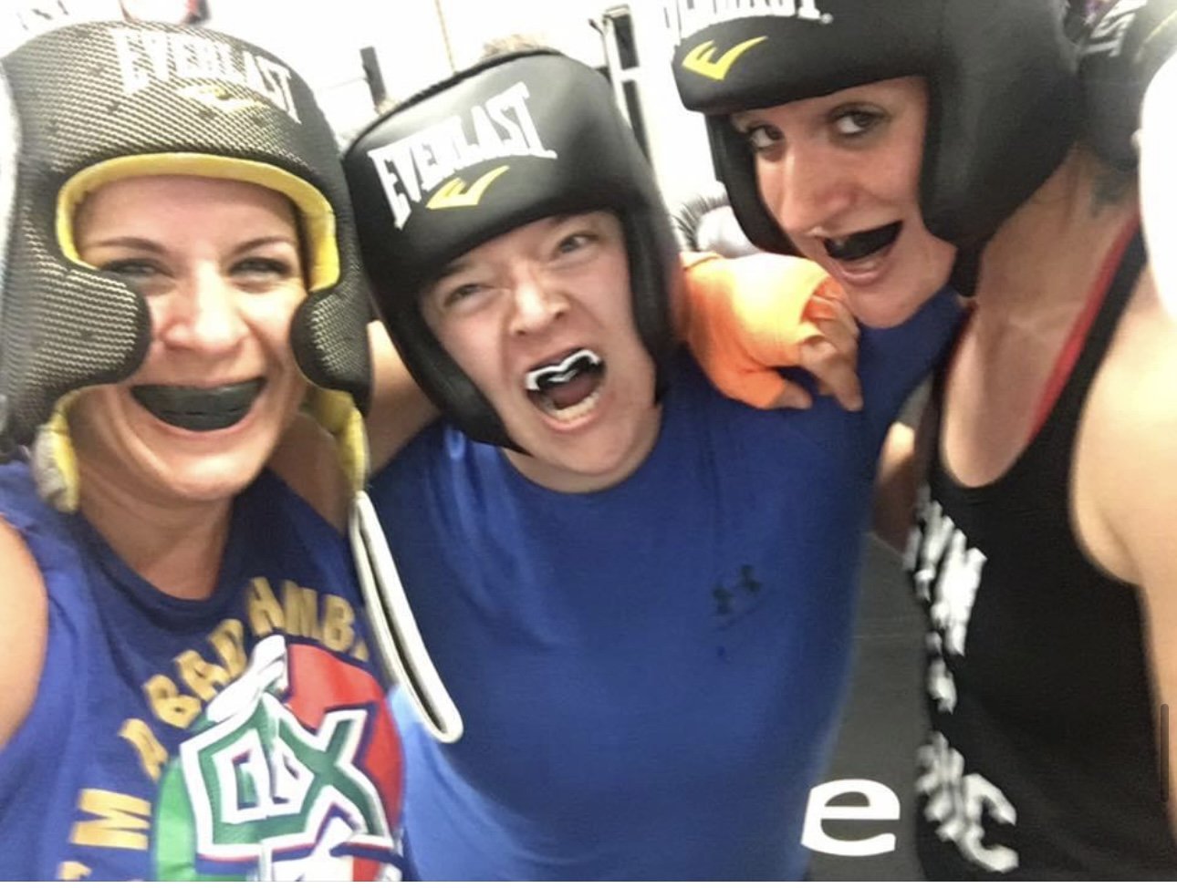 Women's empowerment expert Dr. Alice Atalanta in the gym with two female teammates wearing sparring gear after boxing sparring.