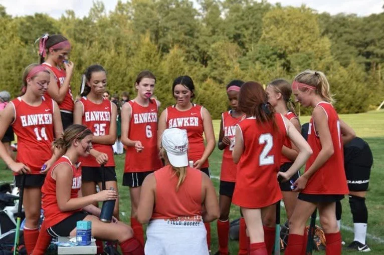 Women's empowerment expert dr. Alice atalanta pictured with the field hockey team she coaches in a serious moment where they are gaining empowerment and confidence