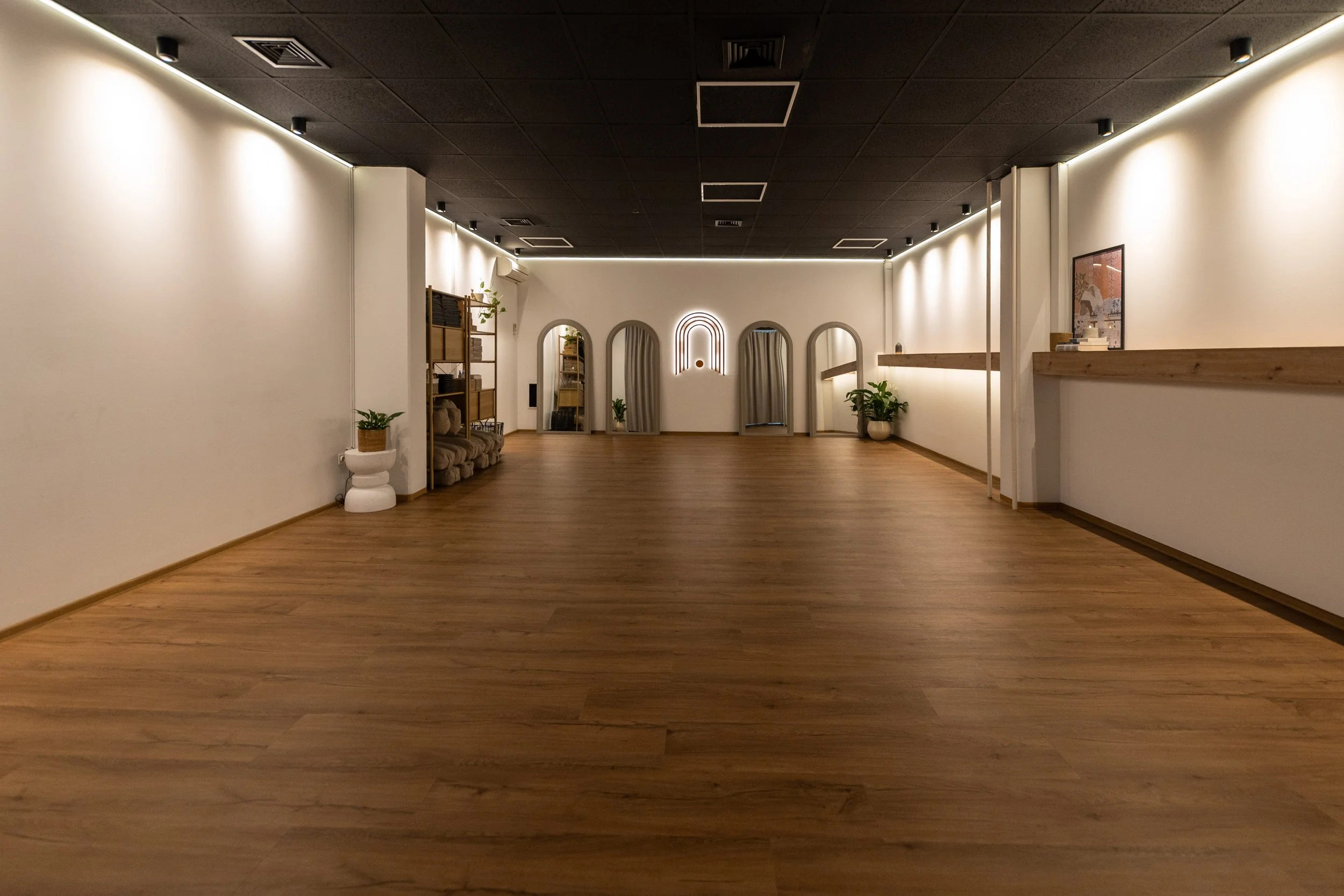 Prazen prostor z lesenimi tlemi, črnim stropom in belimi stenami. Prostor je nežno osvetljen, na eni steni so obokana ogledala in osvetljen logotip Studia Pasaža. Lončnice poskrbijo za prijetno vzdušje.