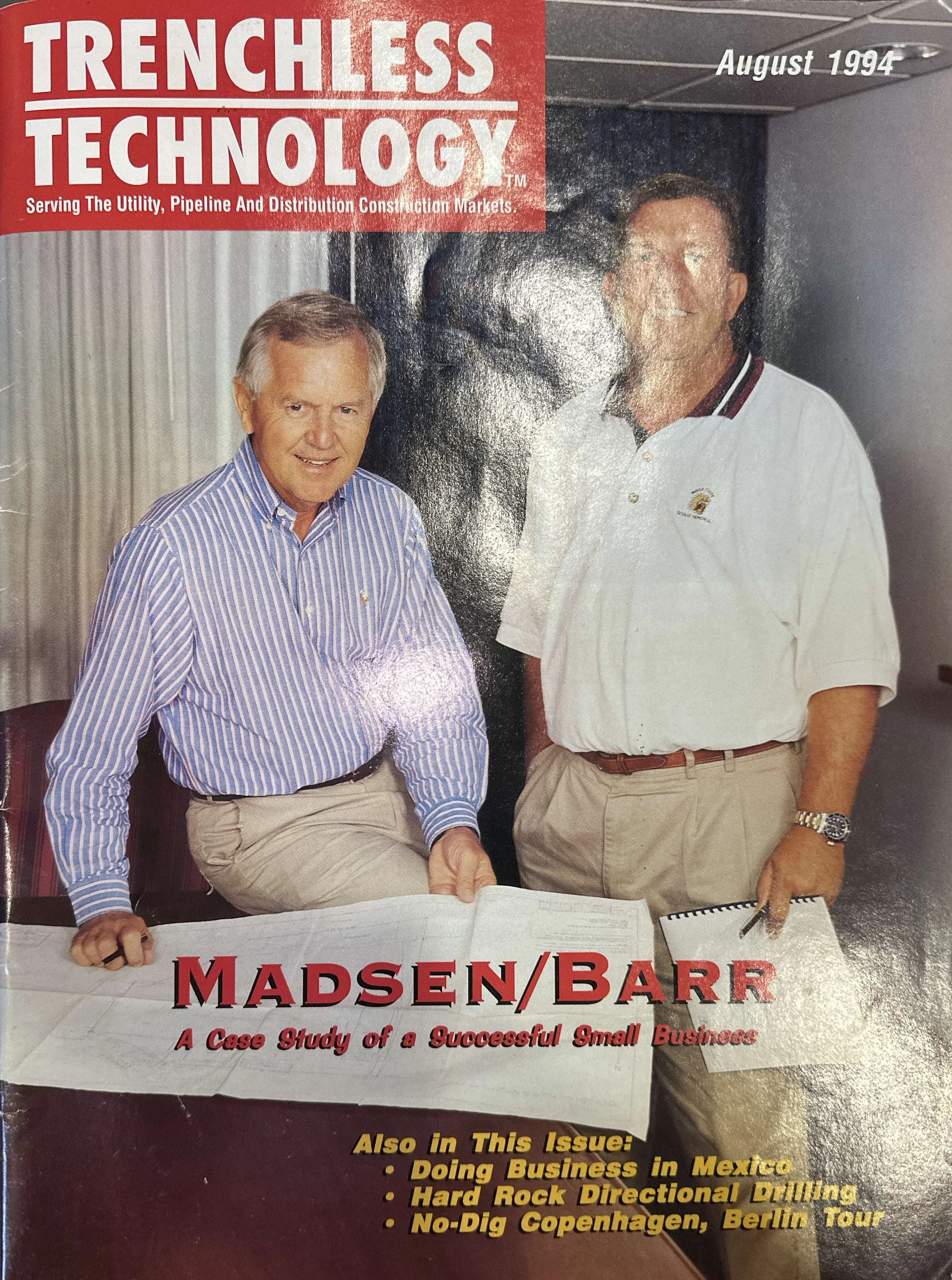 The cover of a magazine titled 'Trenchless Technology' from August 1994. The cover features two men in business casual attire, standing behind a table with documents and notepads, smiling at the camera. The magazine discusses topics related to utility, pipeline, and construction markets, with a case study of a successful small business named Madsen/Barr.