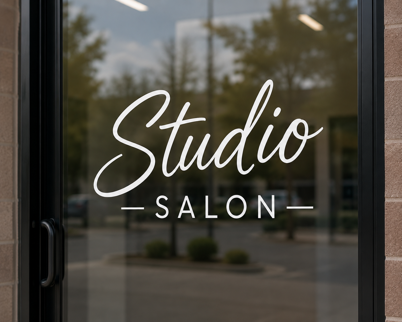 Glass door sign reading 'Studio Salon' in white cursive and block letters, with a reflection of trees and sky in the background.