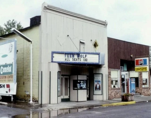 Old movie theater building with a marquee sign that reads 'Teen Wolf All Seats 100' and a ticket booth at the entrance.