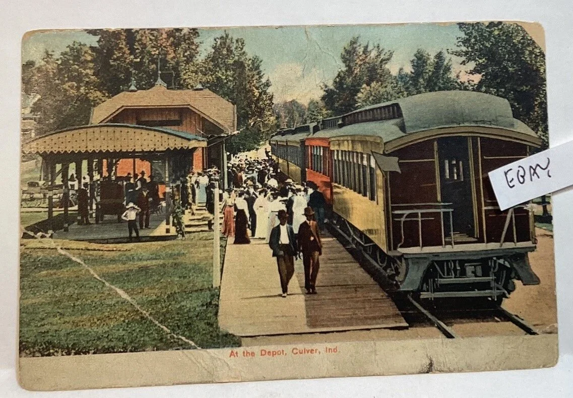 Vintage postcard of a train station at the depot in Culver, Indiana, showing a train on the tracks, a platform, a small building, and people gathered around.