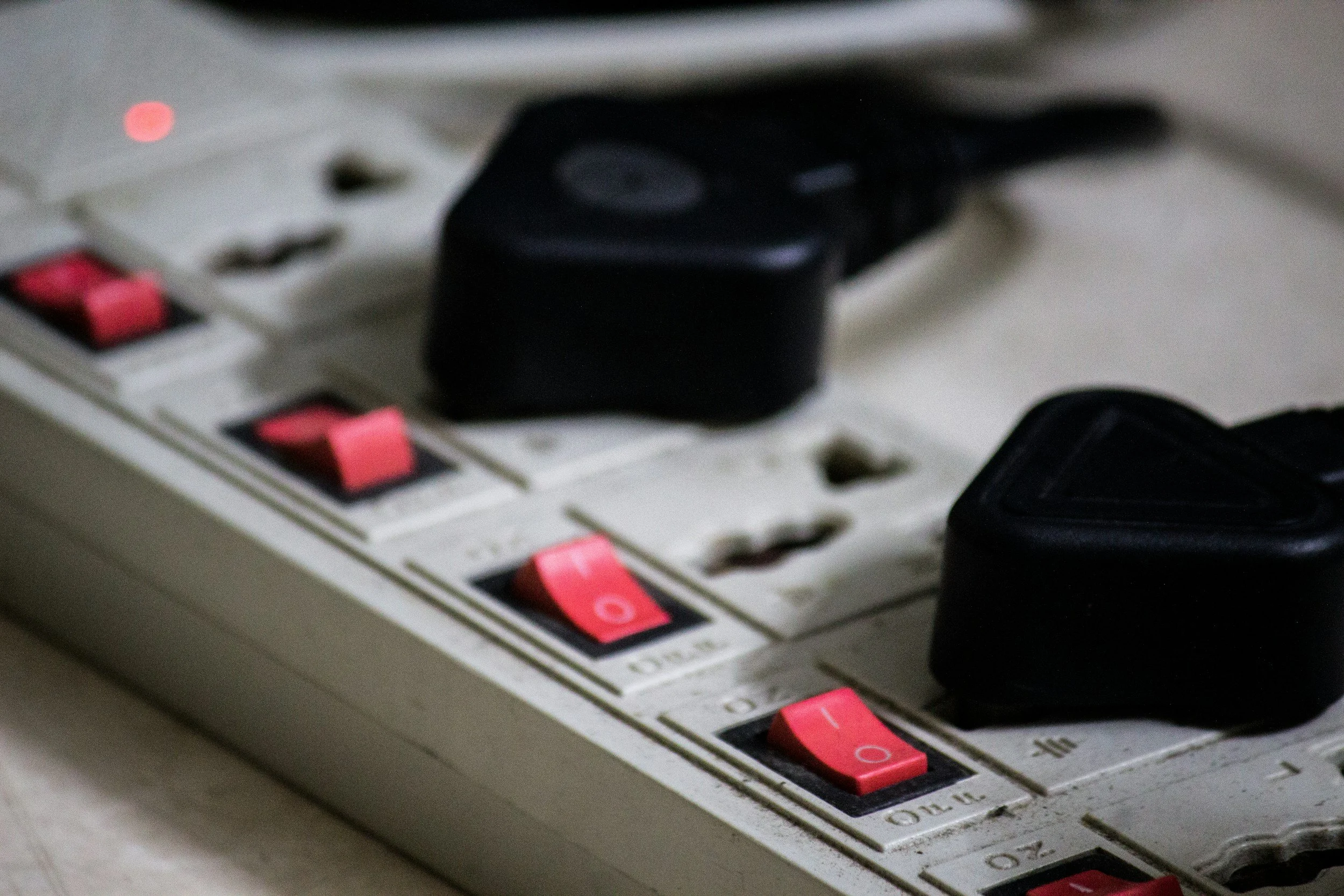 Close-up of an electrical power strip with a black plug inserted and pink switches in the off position.