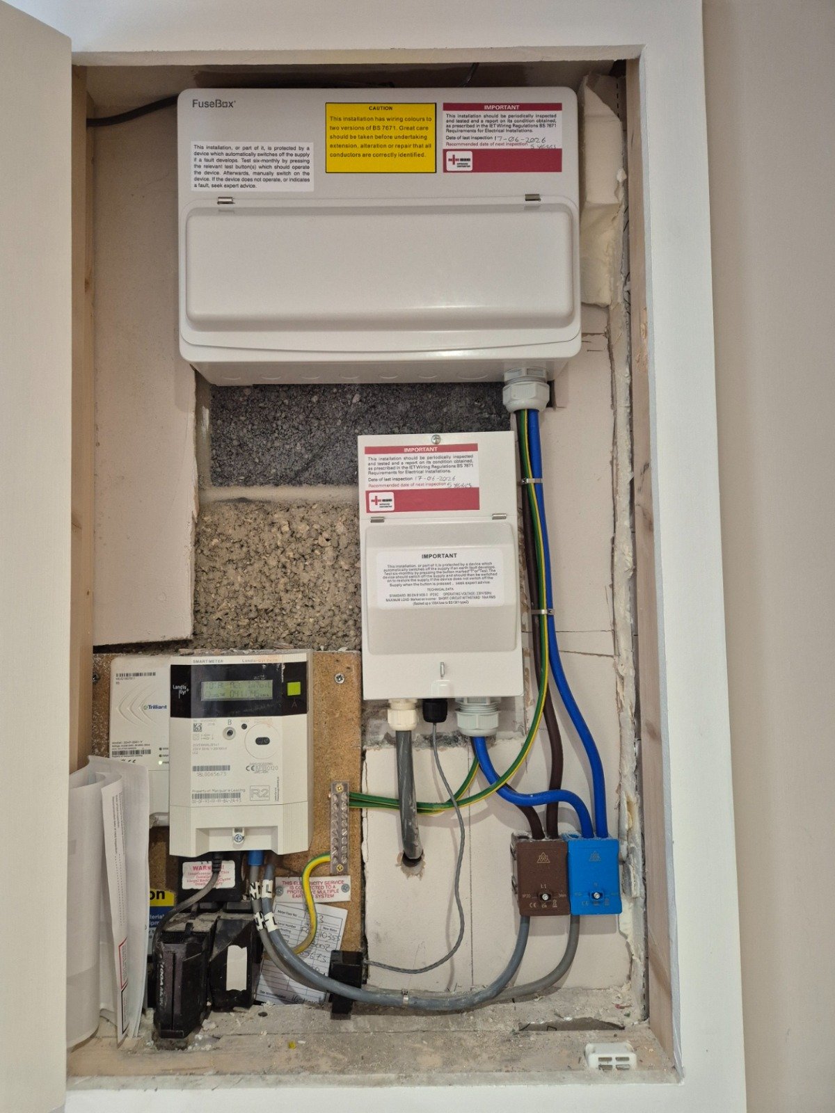 An electrical consumer unit installation with wiring and components in a wall box.