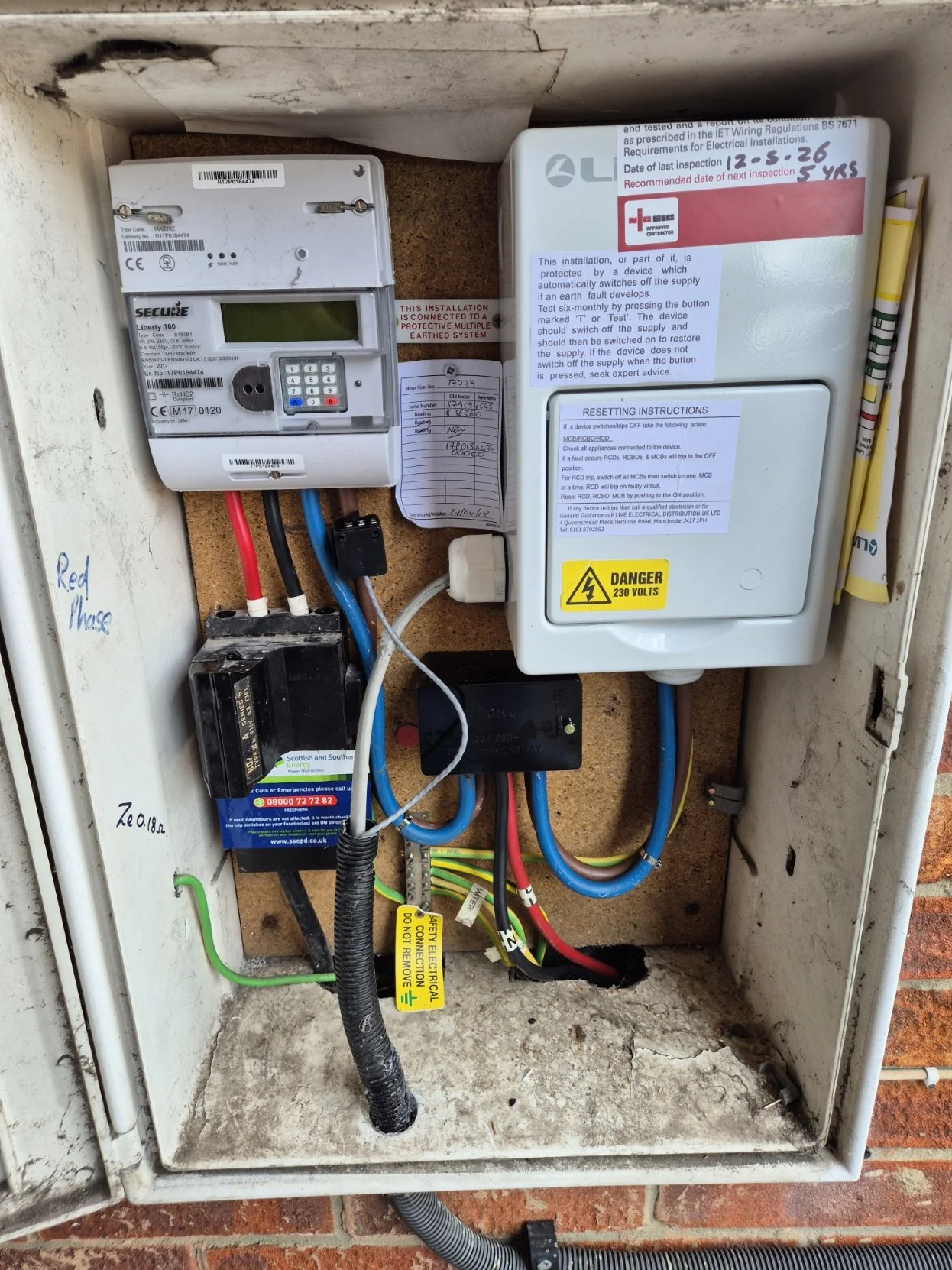 Electrical wiring and meters inside an electrical box, labeled diagram, warning labels, and wiring connections.