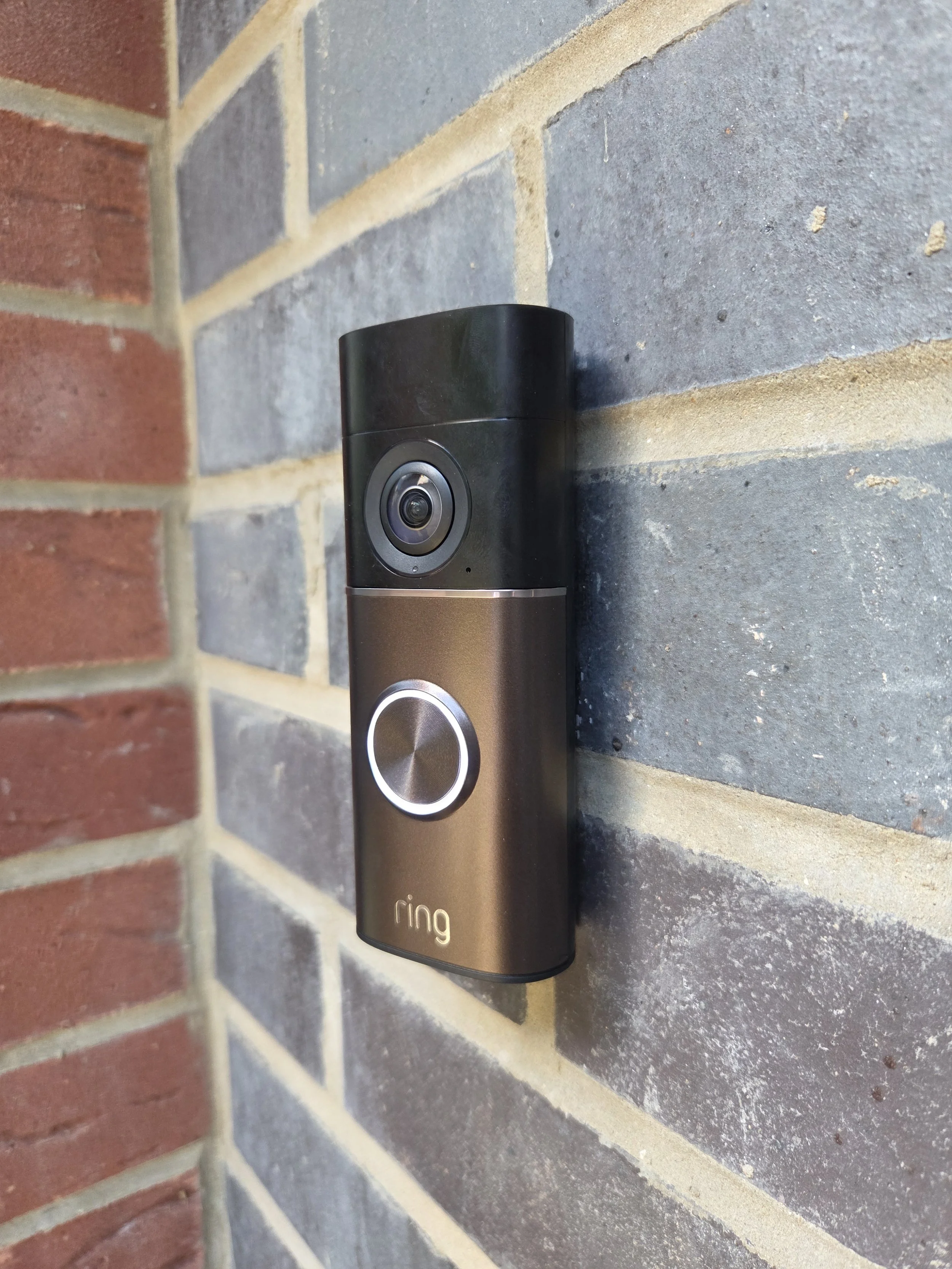 Ring Pro video doorbell mounted on a brick wall beside a black door frame in Borehamwood.