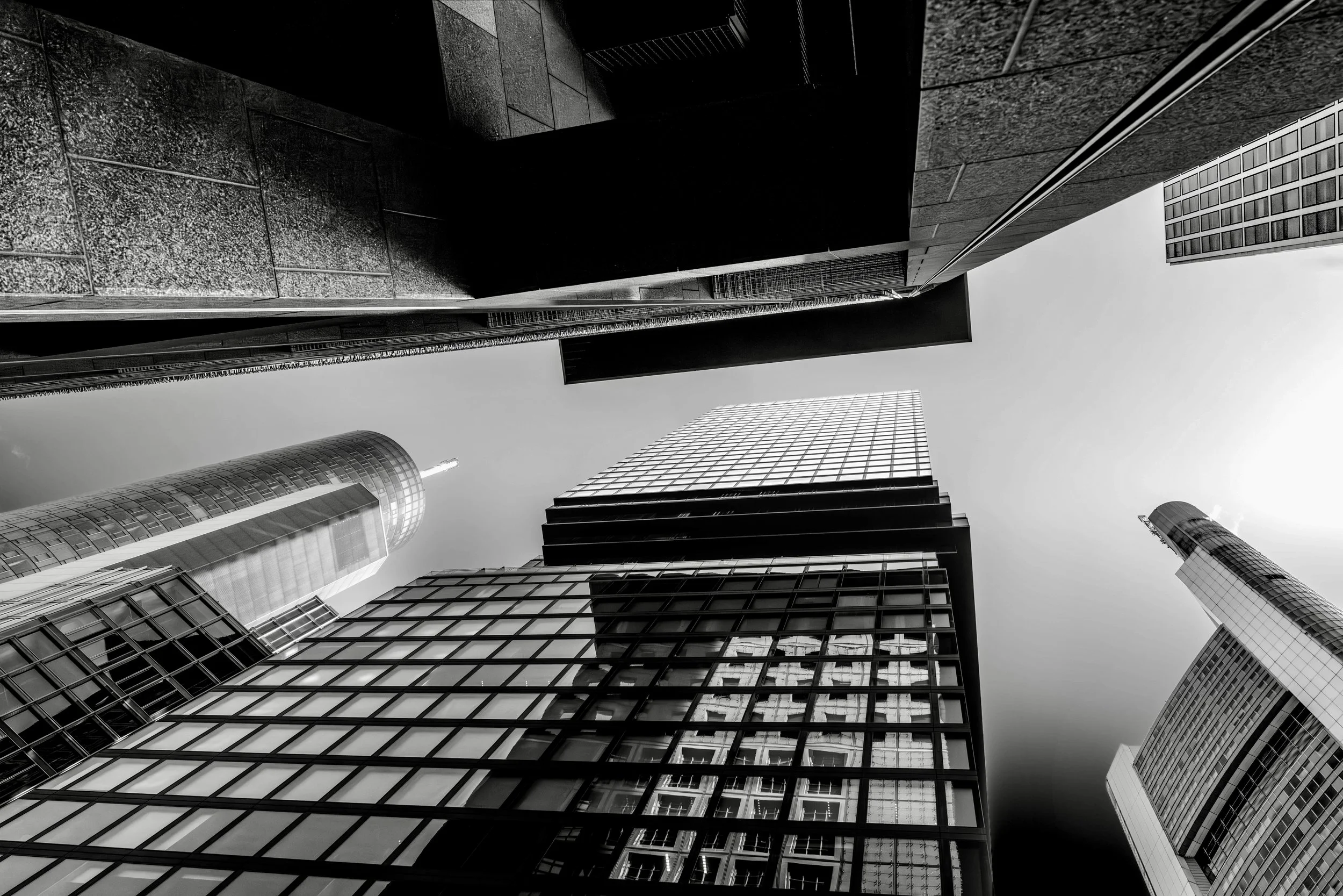 Low-angle view of tall modern office buildings with glass facades in a city skyline, shot in black and white.