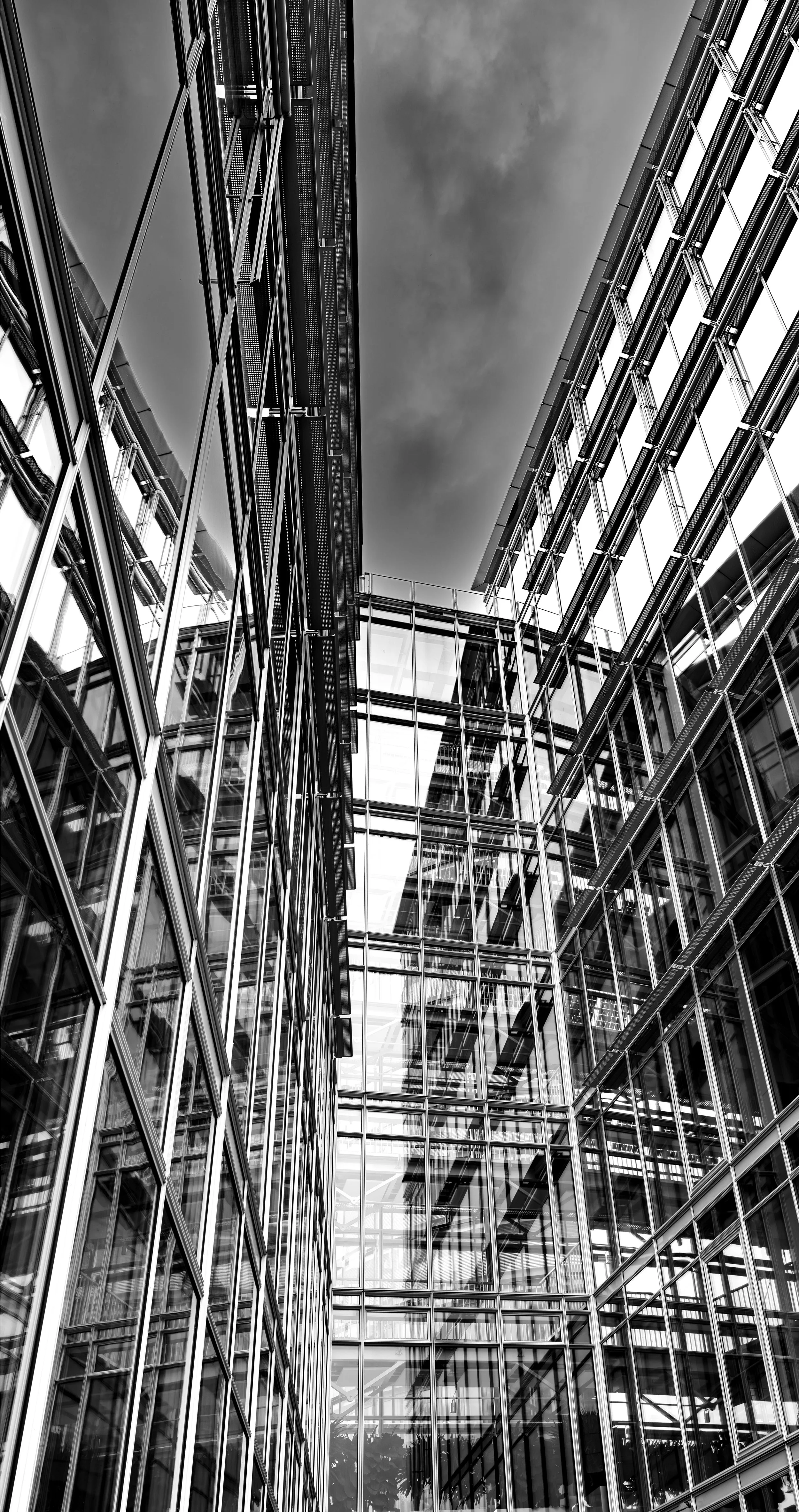 View looking up at modern glass and steel office buildings with reflective windows.