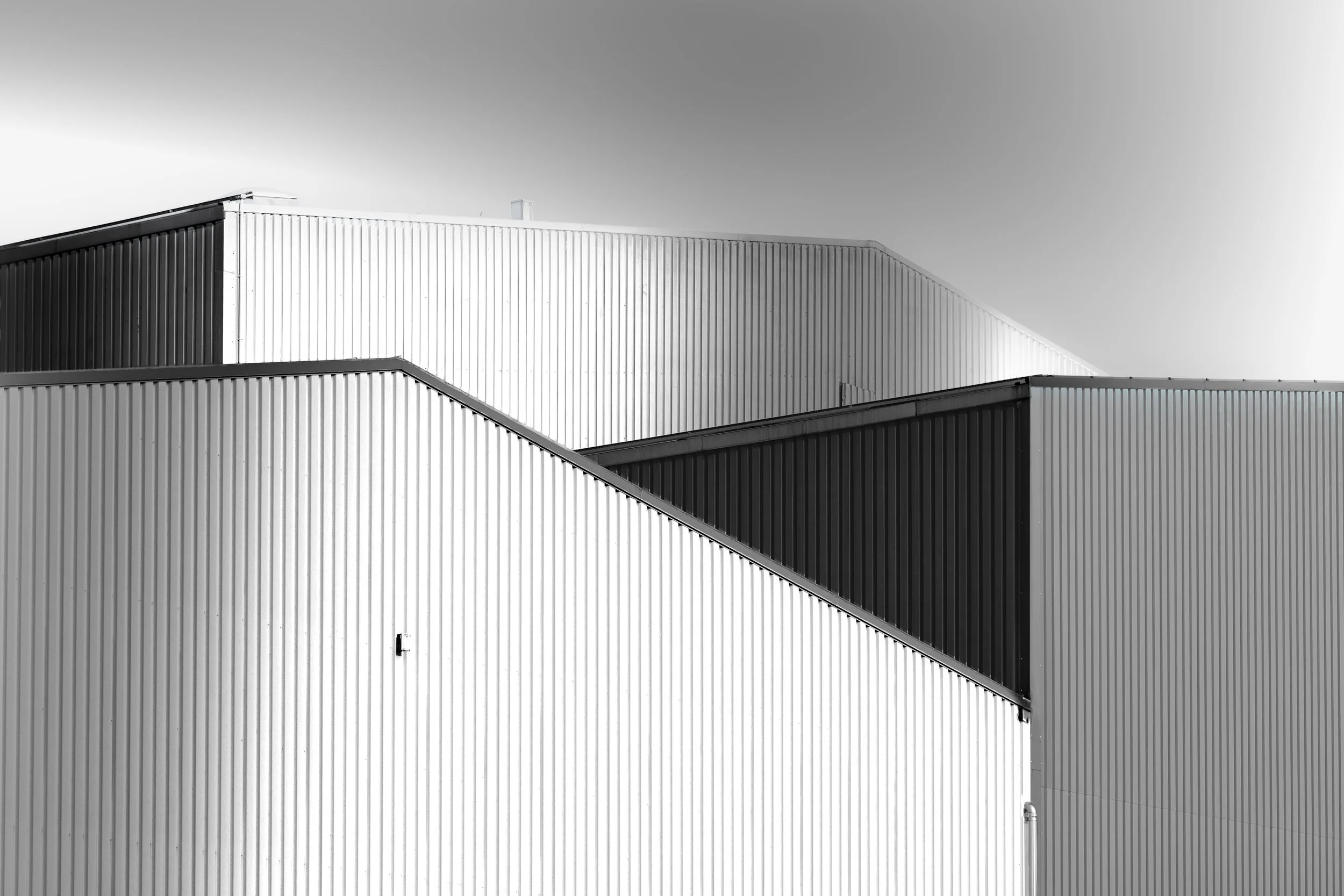 Black and white photo of a modern building with corrugated metal exterior panels and an angular design.