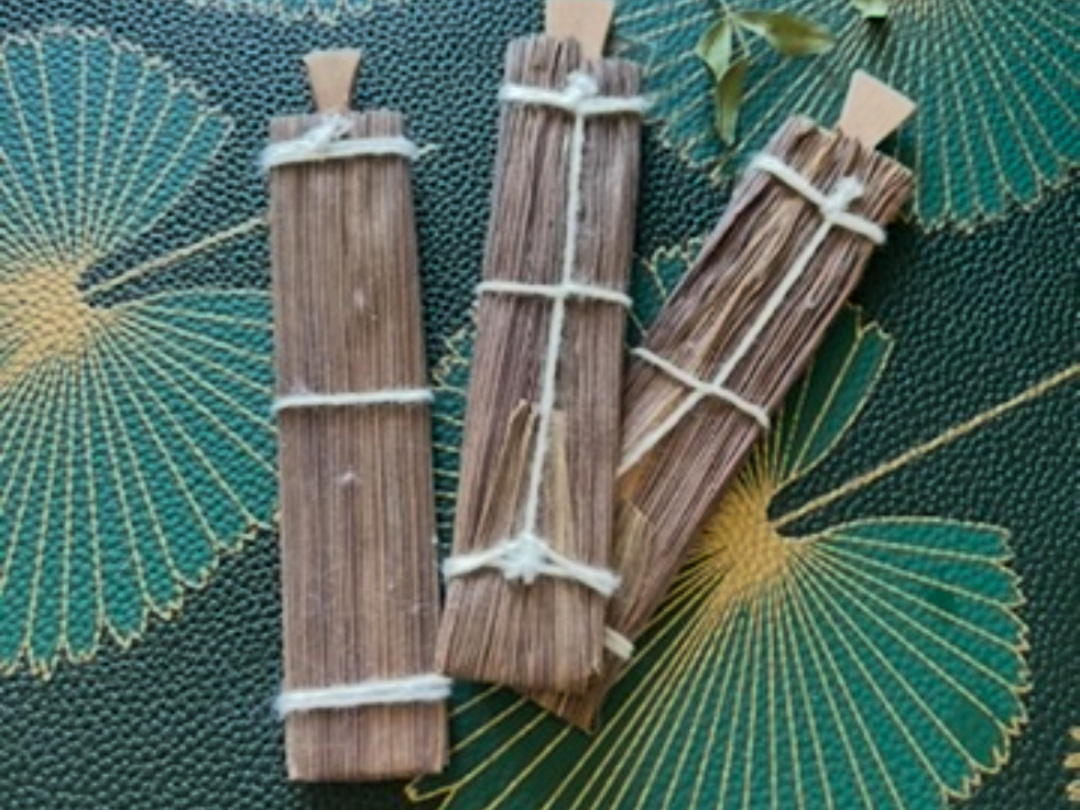 Bundles of dried herbs tied with string on a textured green surface with leaf patterns.