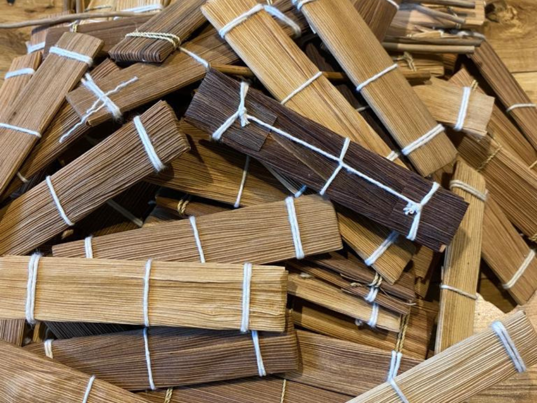 Bundles of Kambo sticks tied with white string, arranged in a pile.
