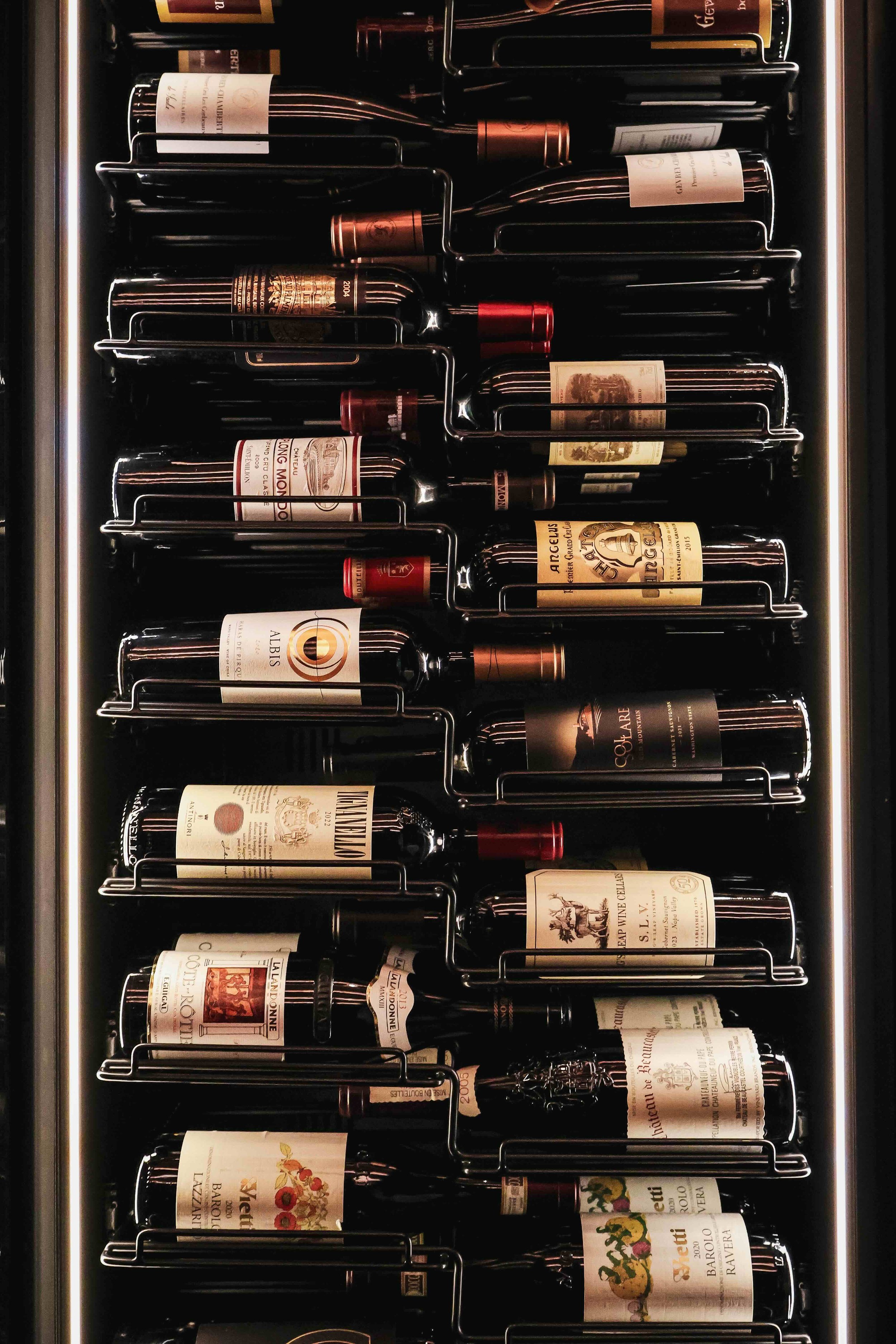 A wine refrigerator filled with various bottles of wine laid horizontally in metal racks.