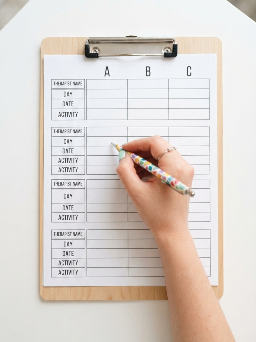 An ABA therapist completing an ABC data collection sheet during a session, recording antecedents, behaviours and consequences to inform clinical assessment