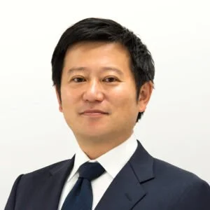 Professional portrait of an Asian man in a dark suit and tie against a plain white background.