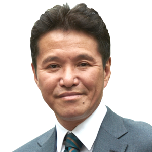 Portrait of a man with black hair wearing a gray suit and tie, smiling slightly against a plain white background.