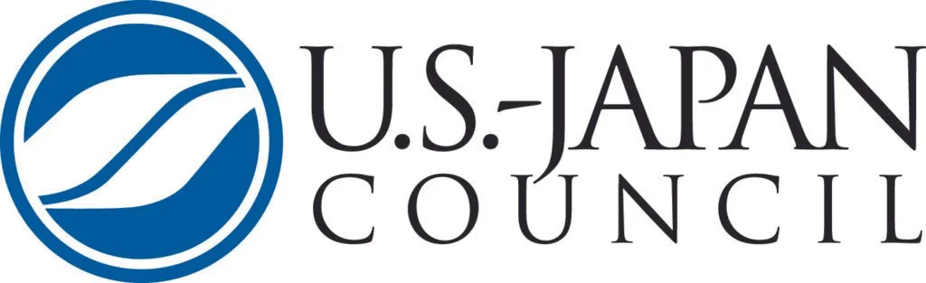 The logo of the U.S.-Japan Council, featuring a blue circular emblem with stylized white waves or lines inside, and the organization name in black text to the right.