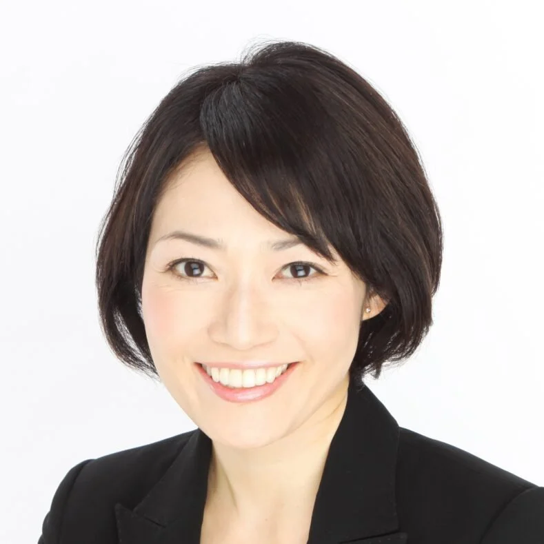 Professional woman with short dark hair smiling in a black blazer against a white background.