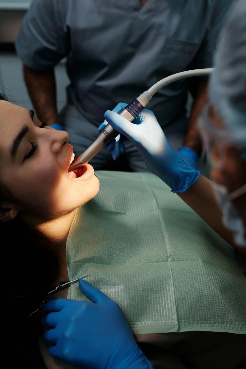Dentist using a curing light on a patient's mouth during a dental procedure.