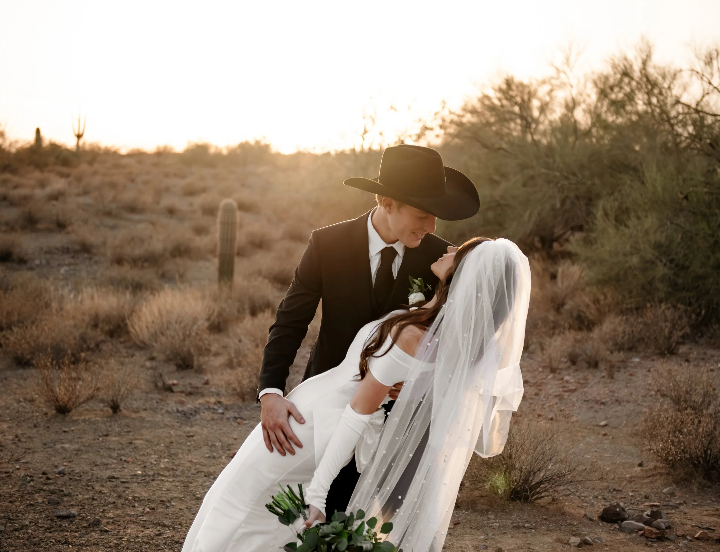 Arizona desert wedding at sunset with Morgan and Kylie DuPuis dancing, featuring a cowboy-style groom, white bridal gown and veil, and scenic desert landscape. Mesa, AZ