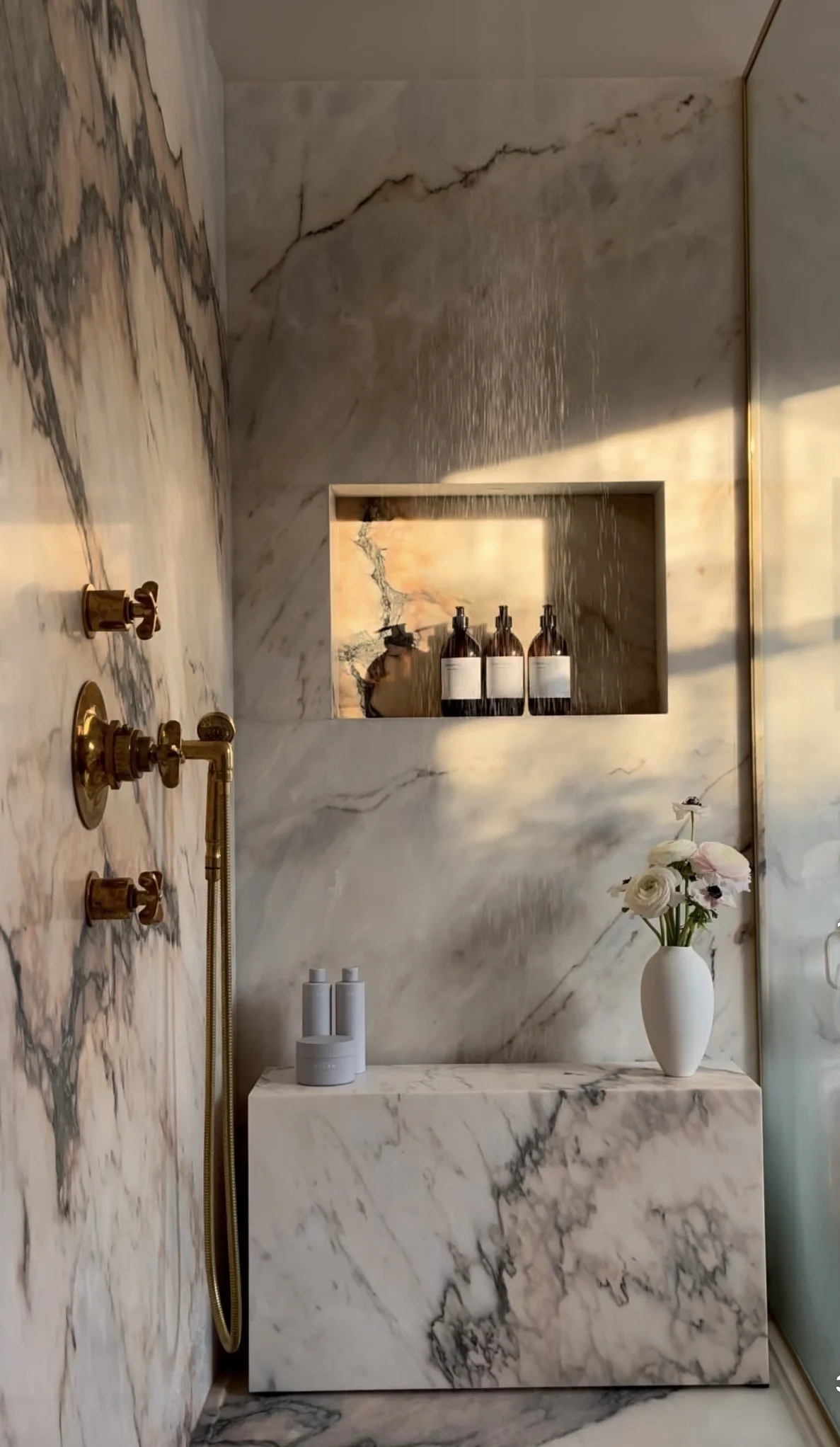 Luxury bathroom remodel in Mesa, Arizona, featuring marble walls and countertops, gold fixtures, built-in shelving, and elegant modern decor.