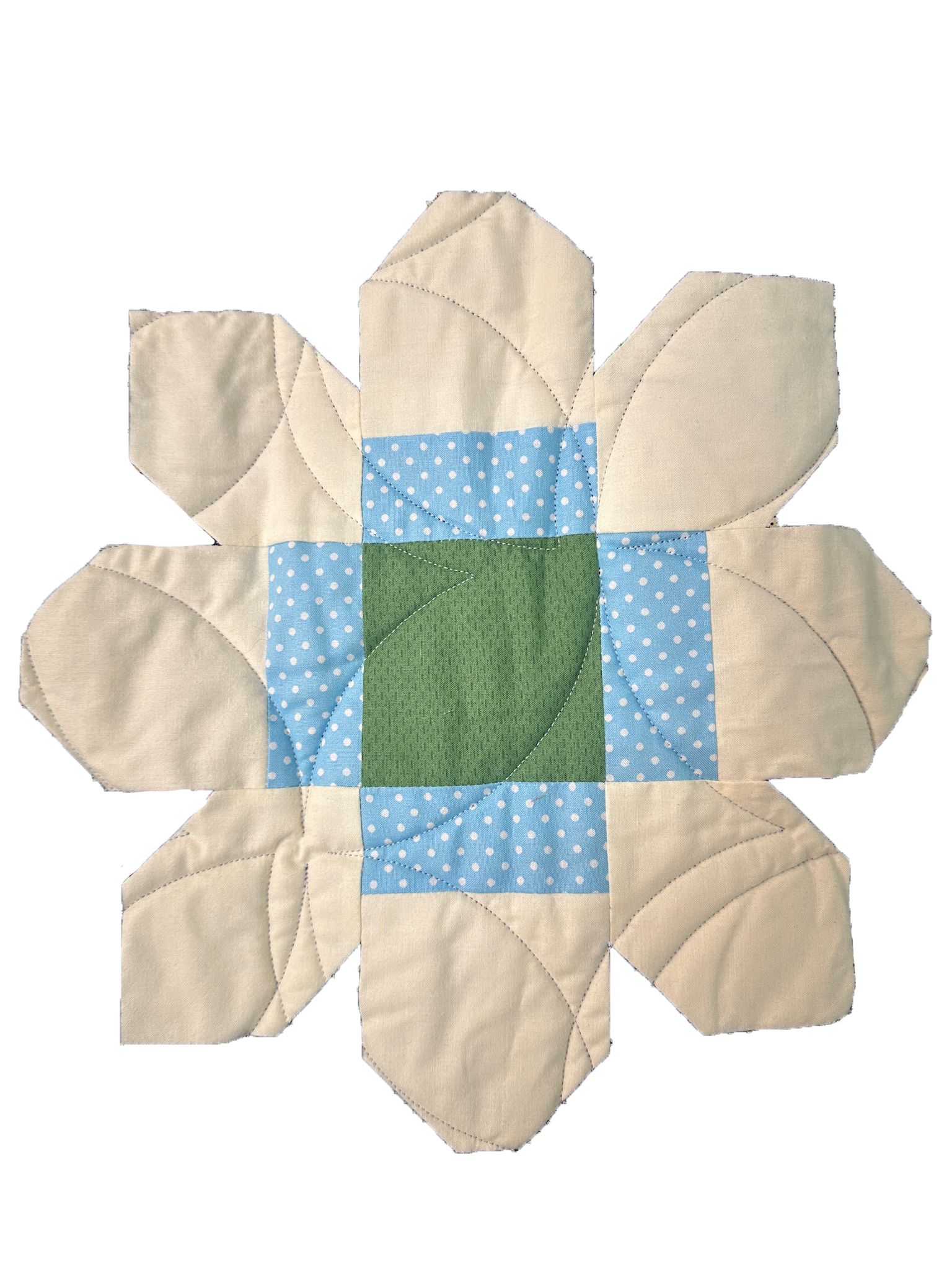 A quilted fabric piece with a flower design, featuring cream-colored petals, a green base, and blue polka-dotted segments.