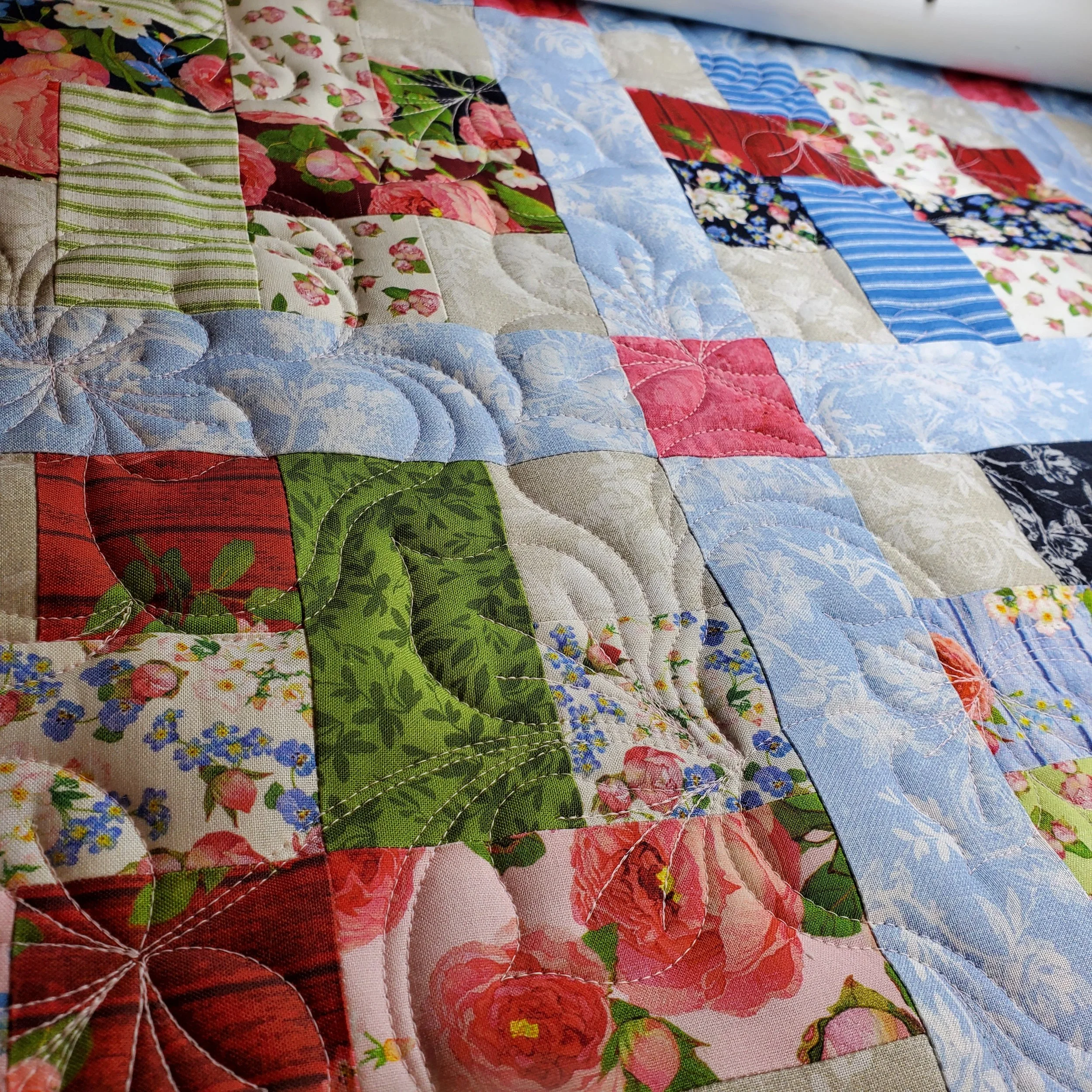 Close-up of a colorful quilt with various floral and striped fabric patches.