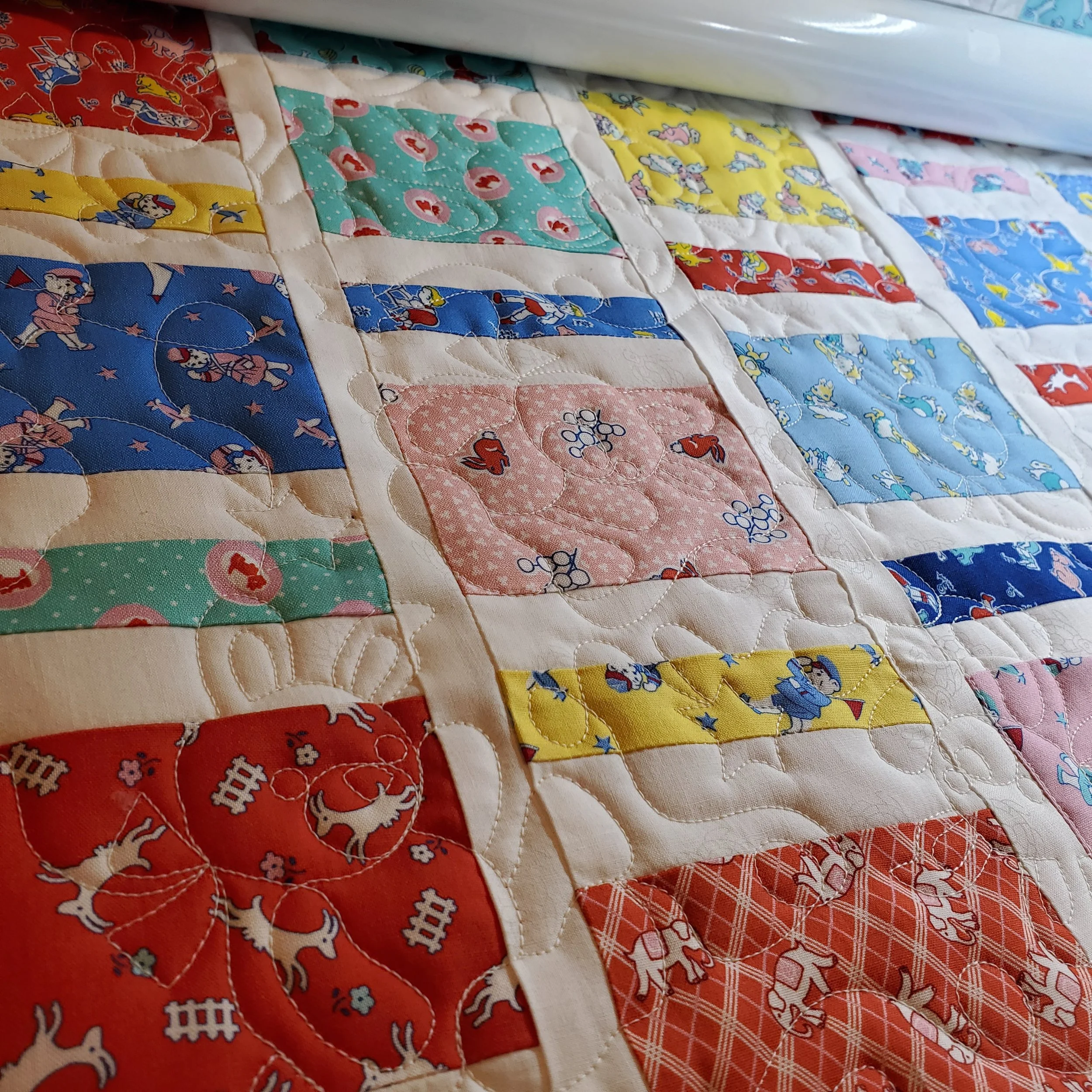 Close-up of a quilt with American flag colors and various patriotic and cartoon characters, including Mickey Mouse, on the fabric squares.