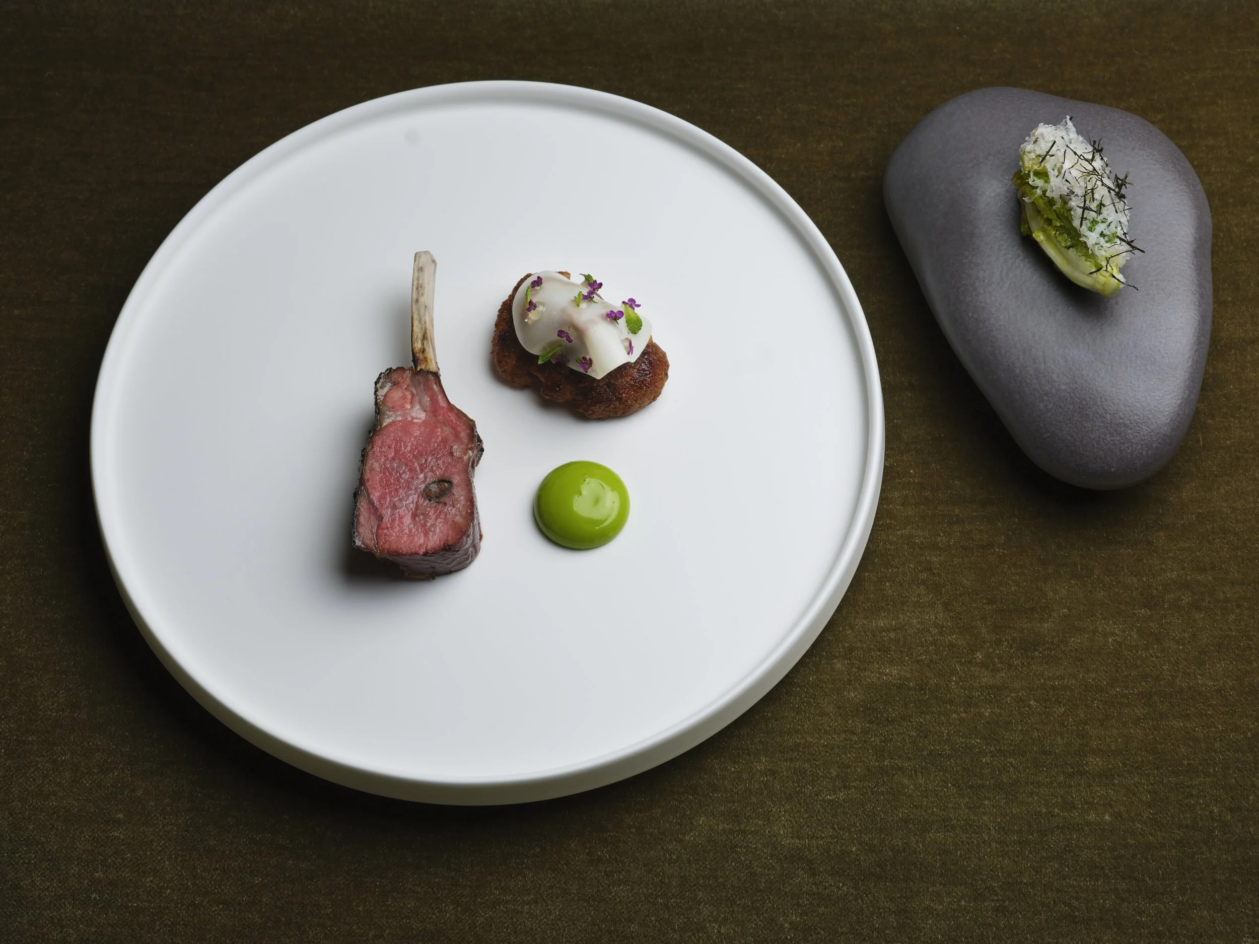 A white plate with kentish lamb cooked medium rare. 