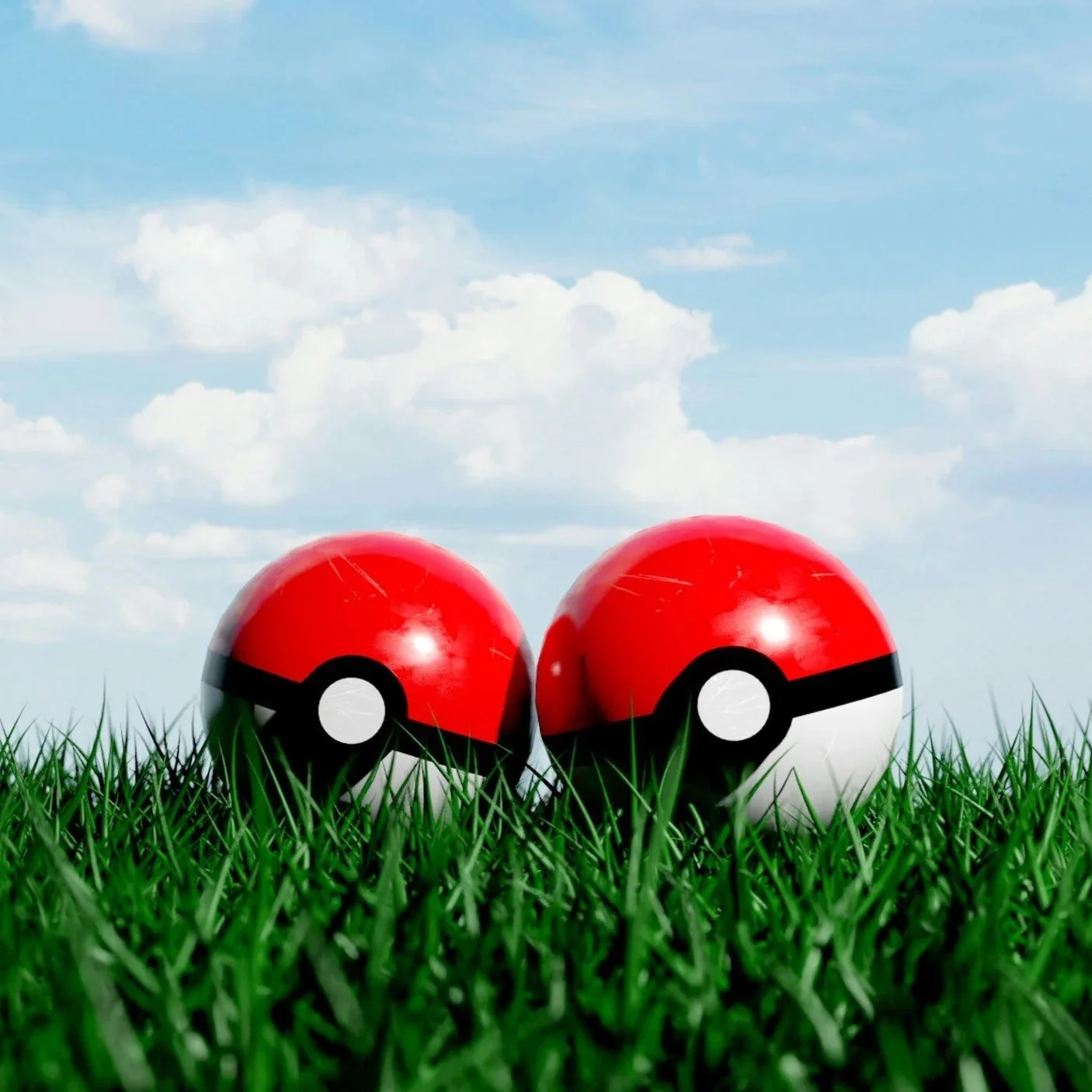 Two red and white Poké Balls placed on green grass with a blue sky and white clouds in the background.