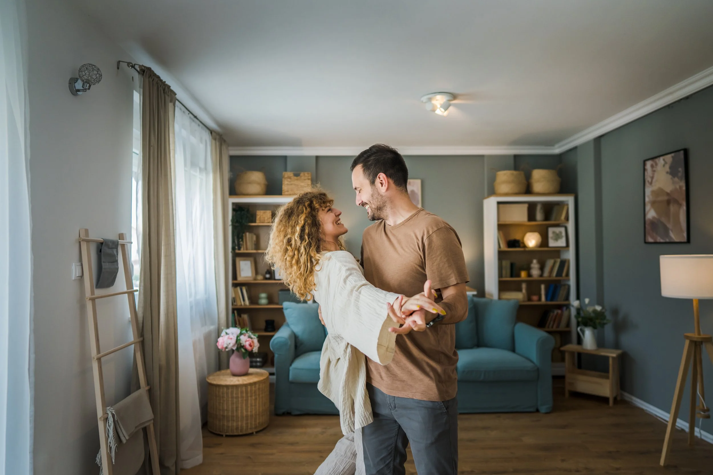 A couple dancing and smiling in a cozy living room.