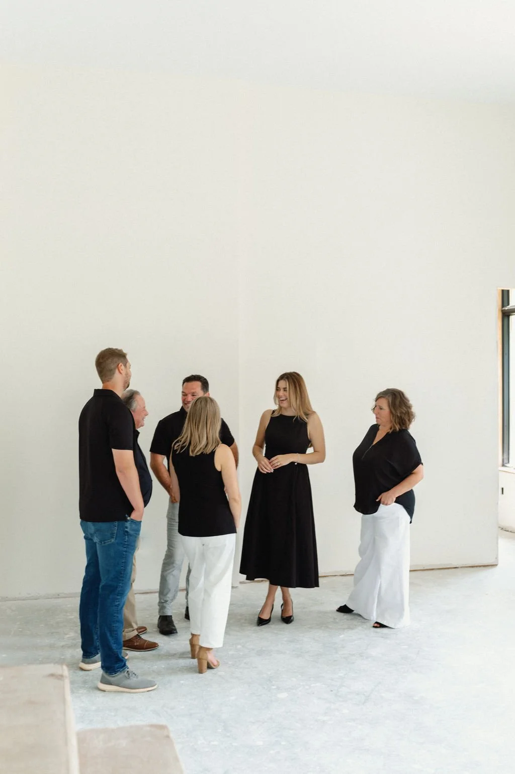RedKnot Custom Homes team standing and talking in a spacious, minimally decorated room with a large window to the right.