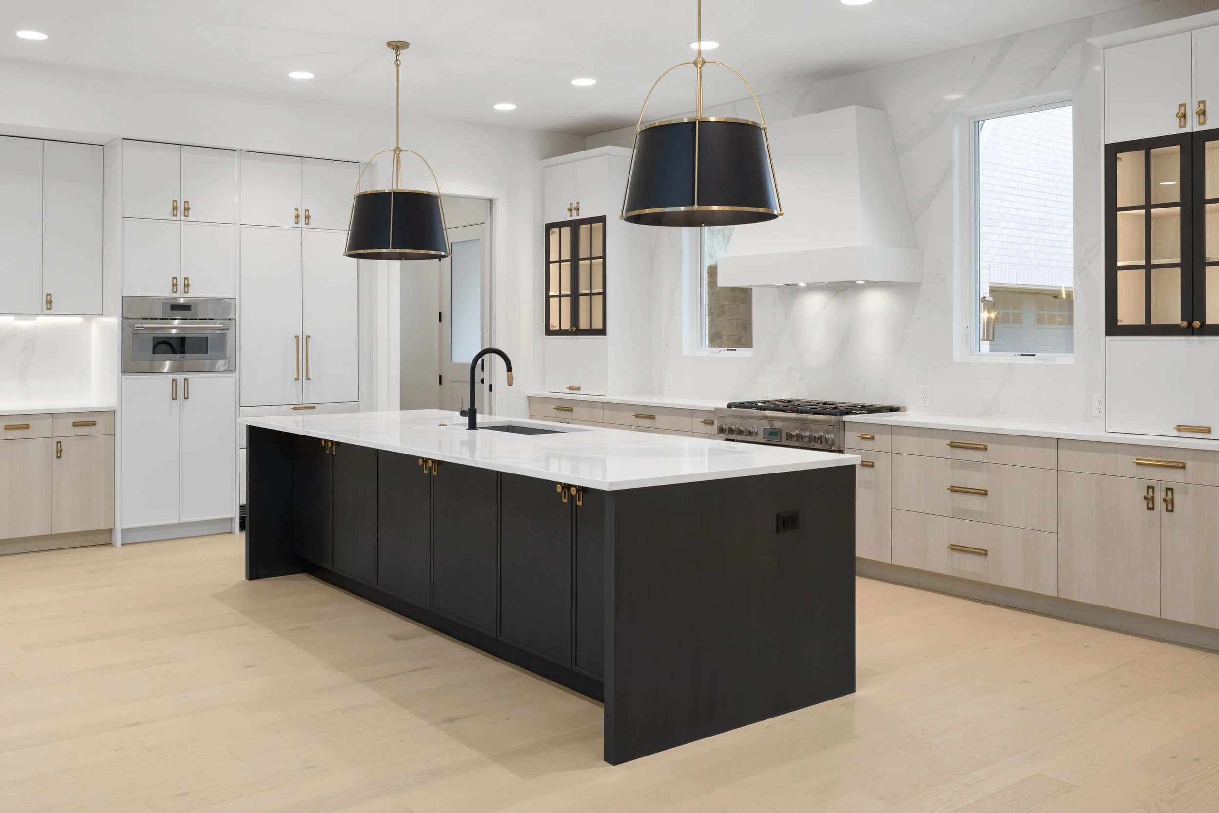 Open concept kitchen with black and brass finishes and oversized kitchen island