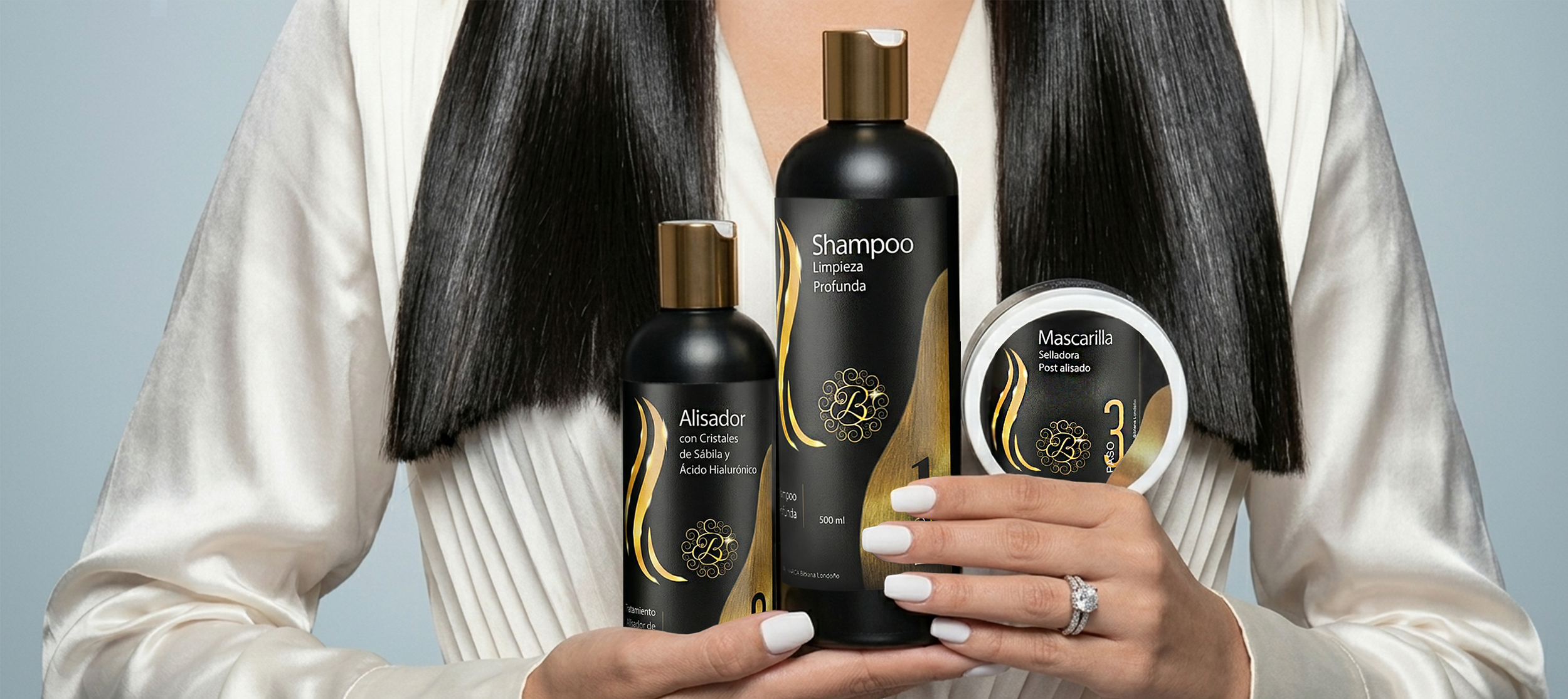Una mujer con cabello liso y oscuro sostiene productos de cuidado capilar en sus manos. Los productos incluyen un shampoo, un alisador con cristales de sándalo y ácido hialurónico, y una mascarilla selladora post alisado, todos con envases negros y detalles dorados.