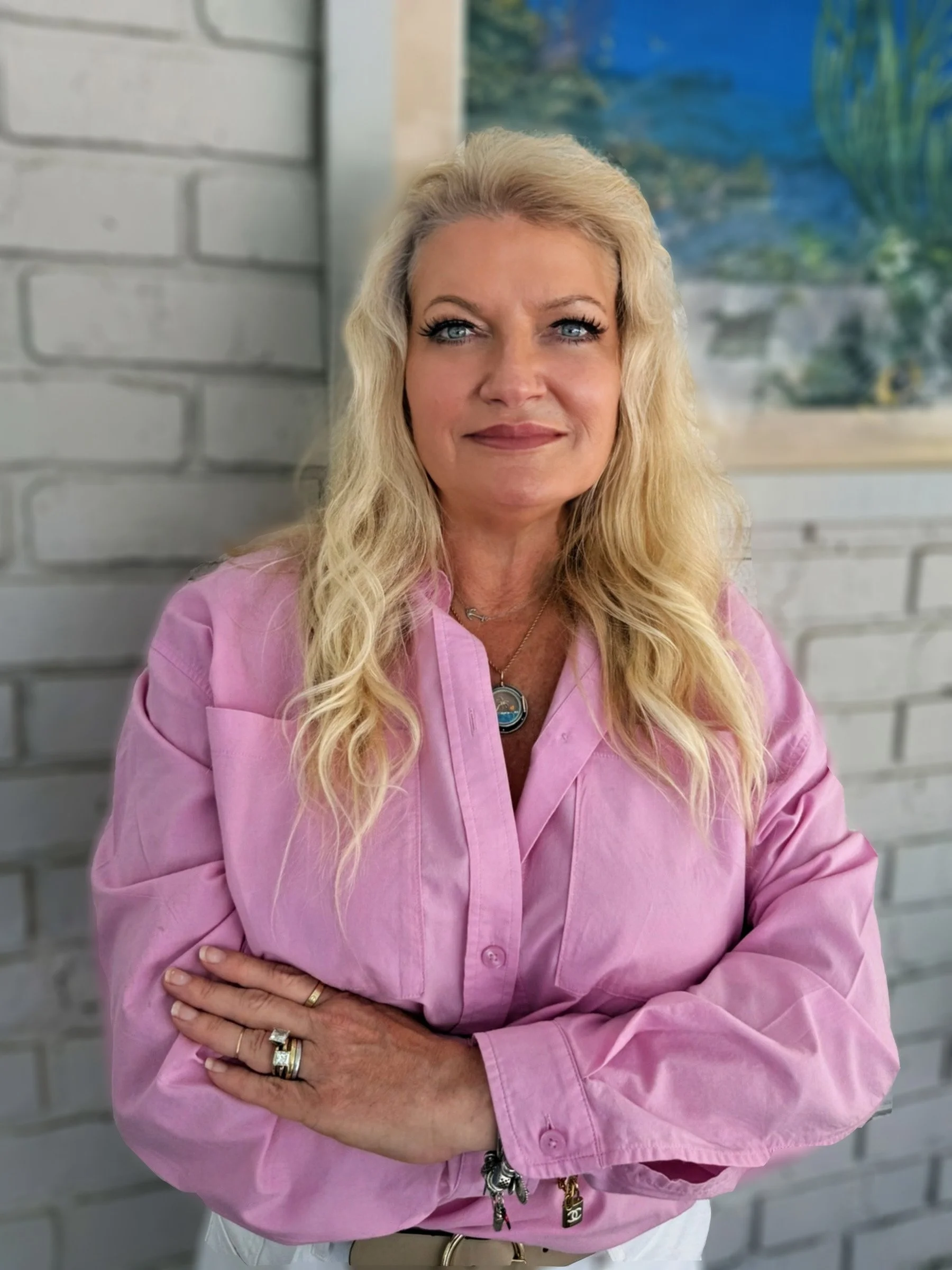 image of Ko Robins - woman standing with arms crossed wearing a pink shirt