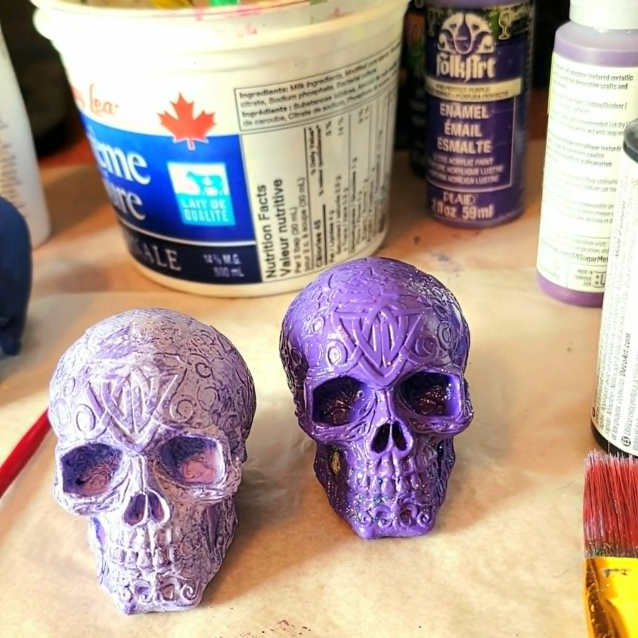 Various purple decorative skulls with intricate patterns, placed on a store shelf alongside other products.