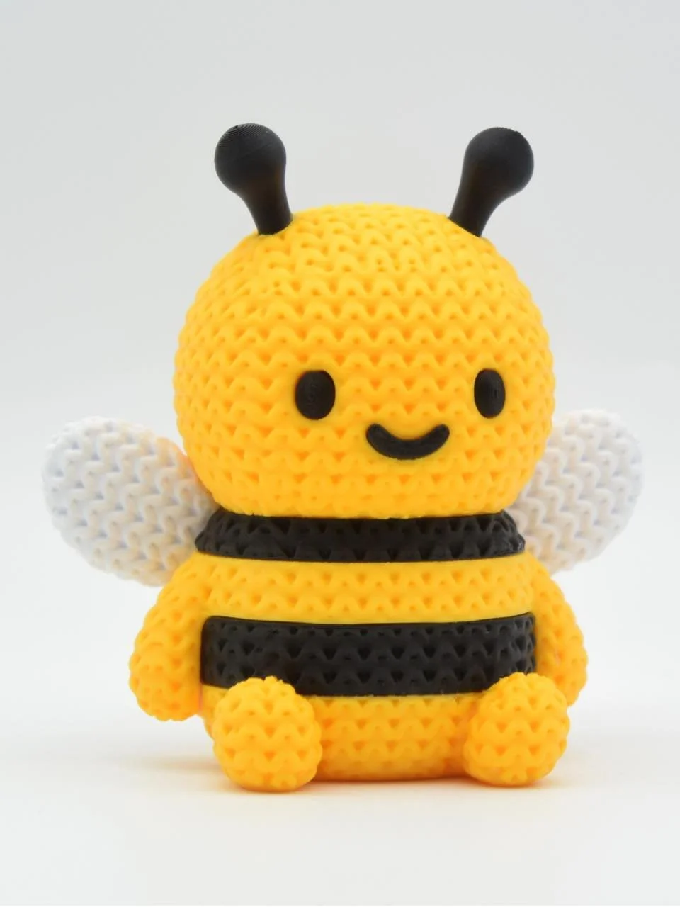 Knit-style bee figurine with a yellow and black striped body, white wings, and a smiling face.