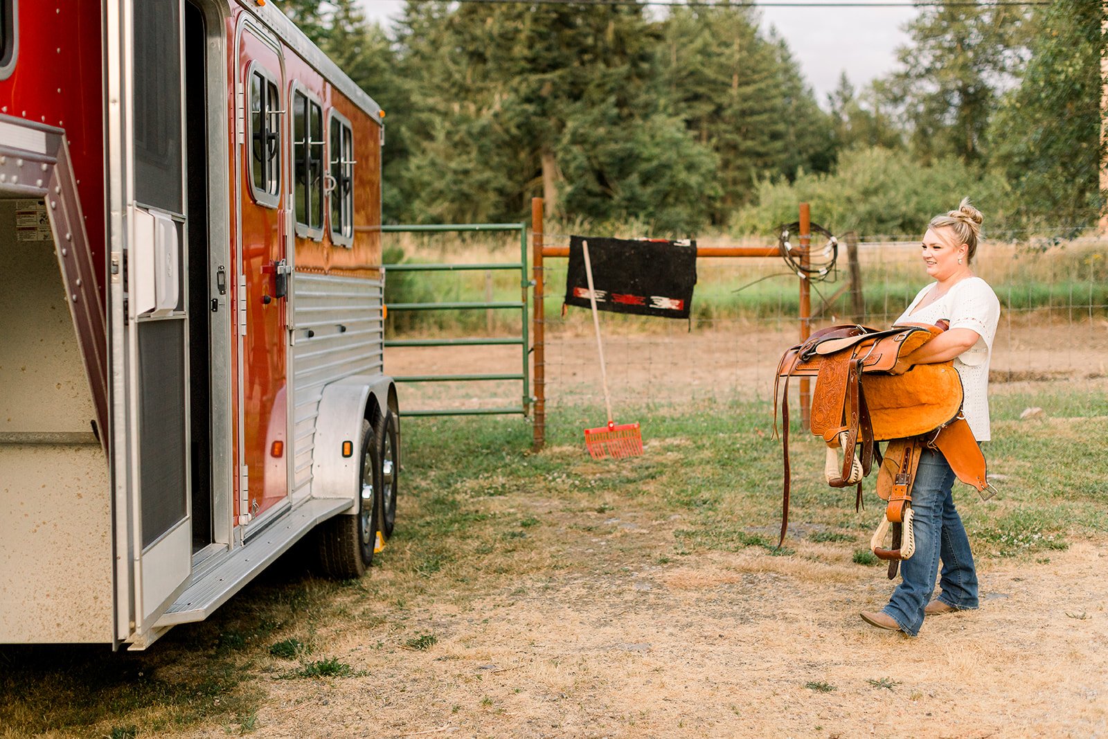 Saddling horses beside a horse trailer on a rural property in Eatonville, Washington.