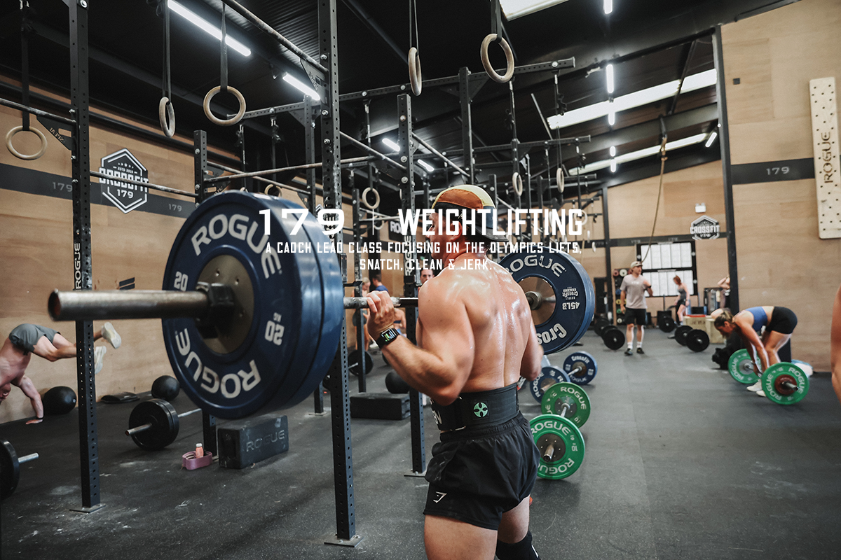 A person in a gym lifting barbells with weights on a squat rack, surrounded by gym equipment and other people working out.