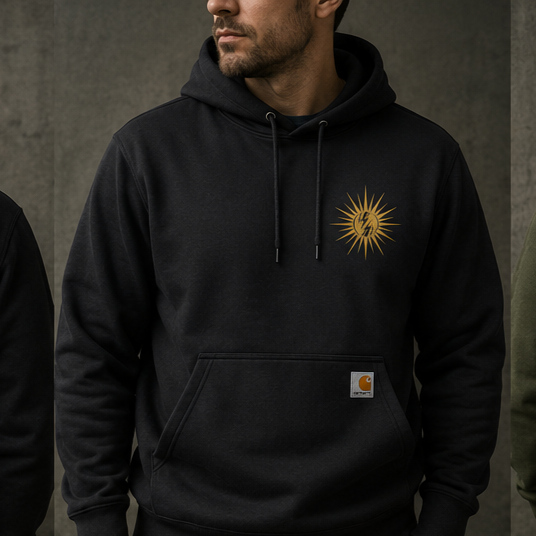 A man wearing a black hoodie with a golden sun and lightning bolt graphic on the chest, standing against a plain background.