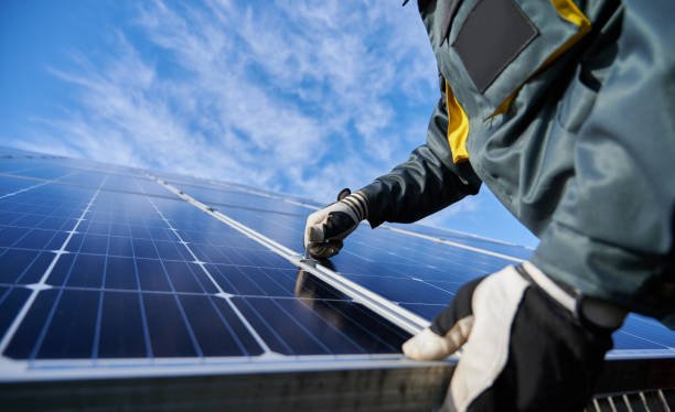 Person installing solar panels outdoors under a cloudy sky