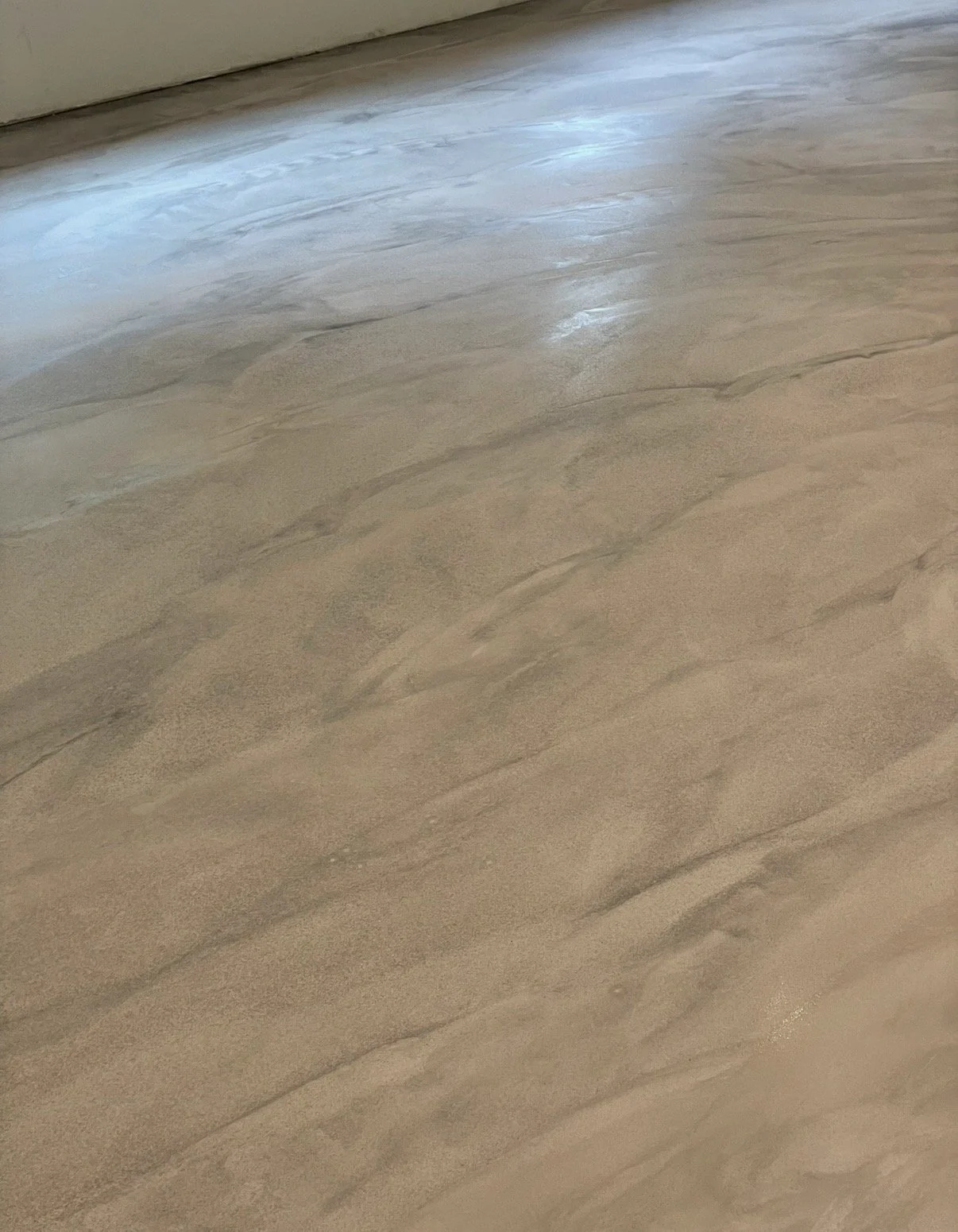 Billedet viser et gulv med en marmorlignende overflade med grå og beige nuancer og naturlige mønstre.