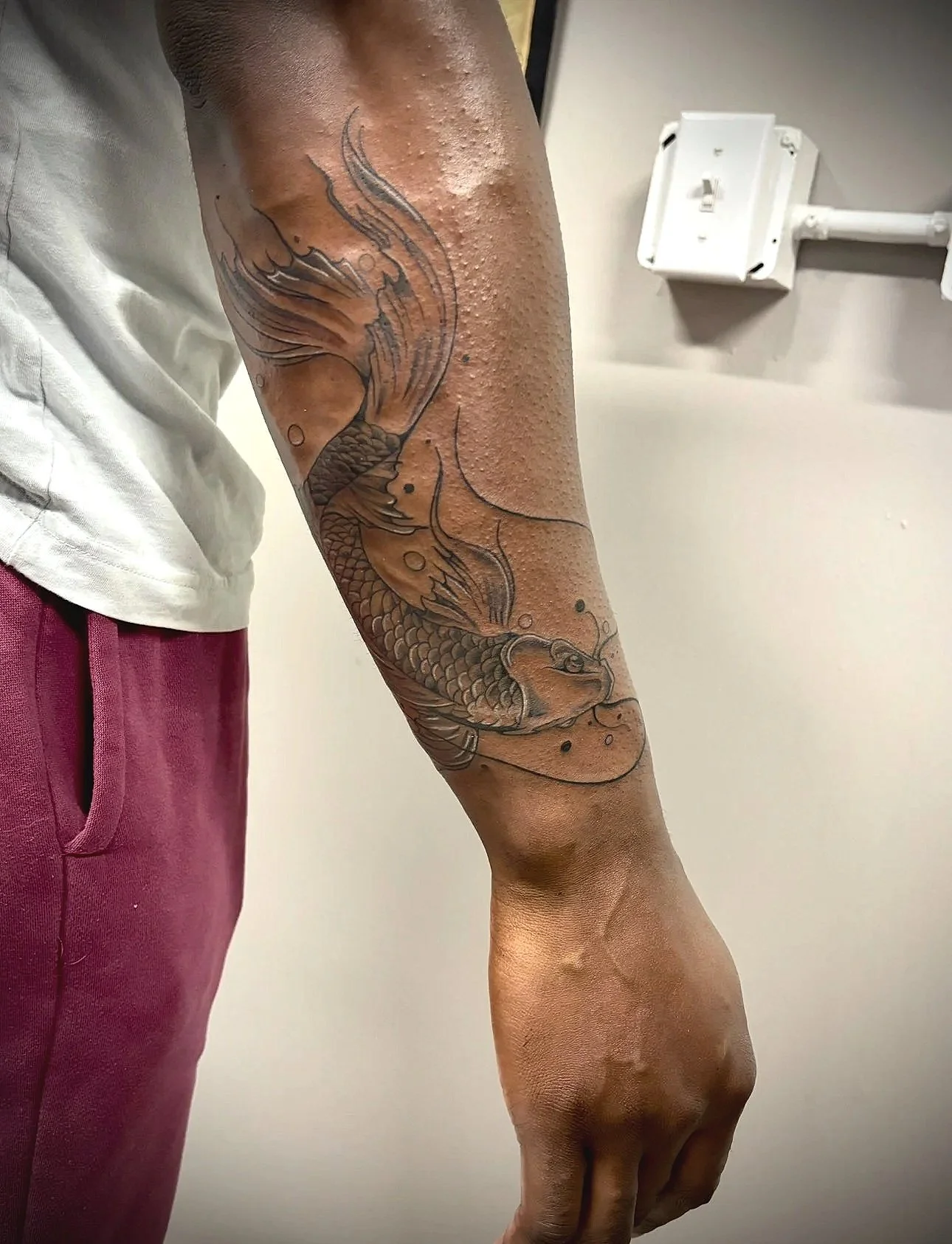 Tattoo of a koi fish on a man's forearm.