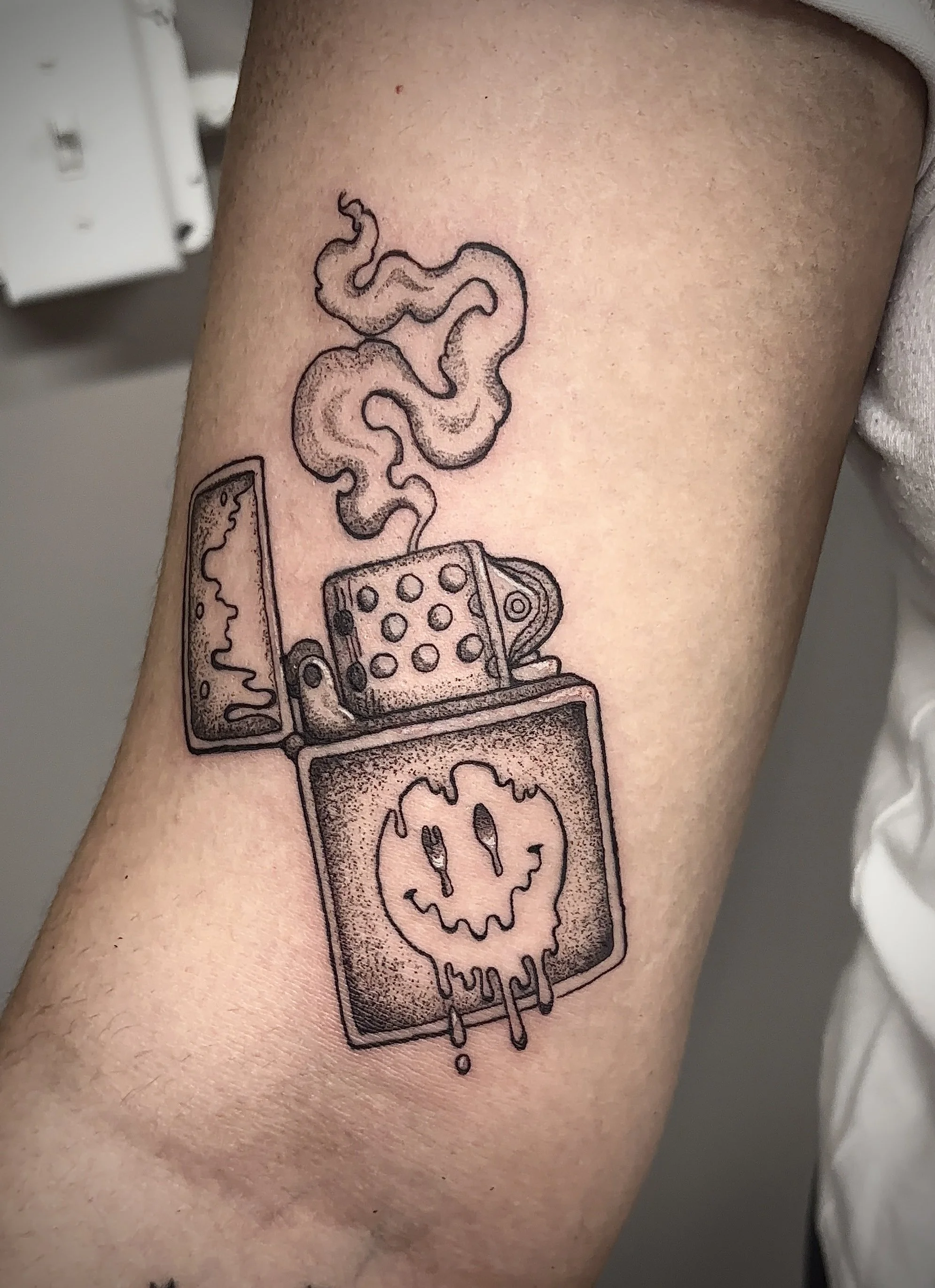 A surreal tattoo of a lighter with smoke rising from it, inside a rectangular border with a melting effect.