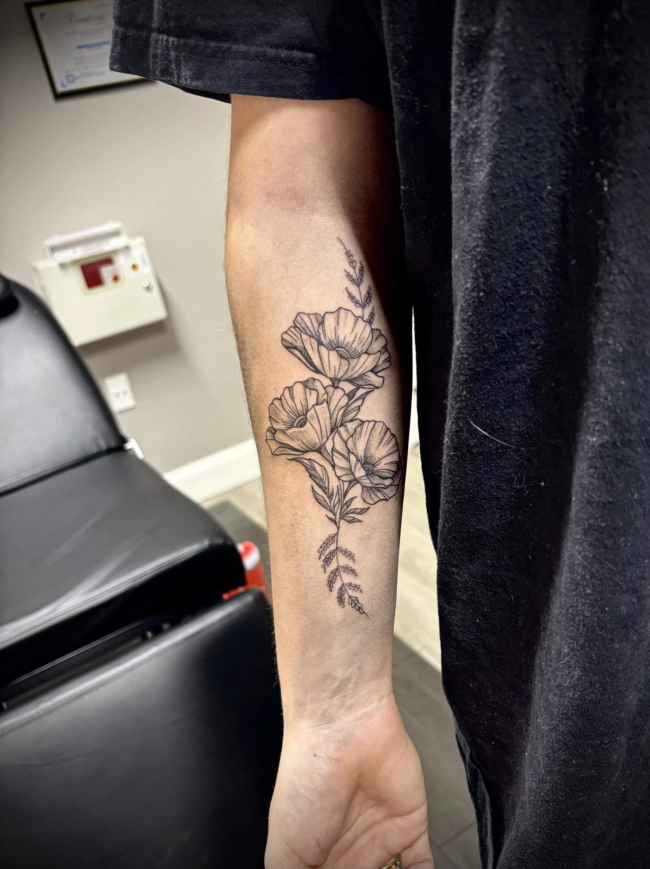 A person's arm with a floral tattoo, including flowers and leaves, visible in a setting that appears to be a medical environment.