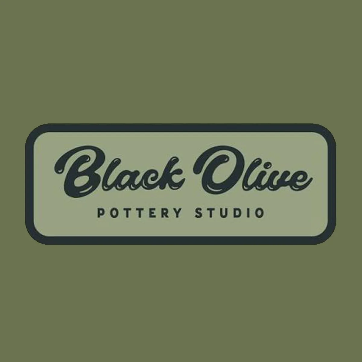 Sign for Black Olive Pottery Studio on a green wall.