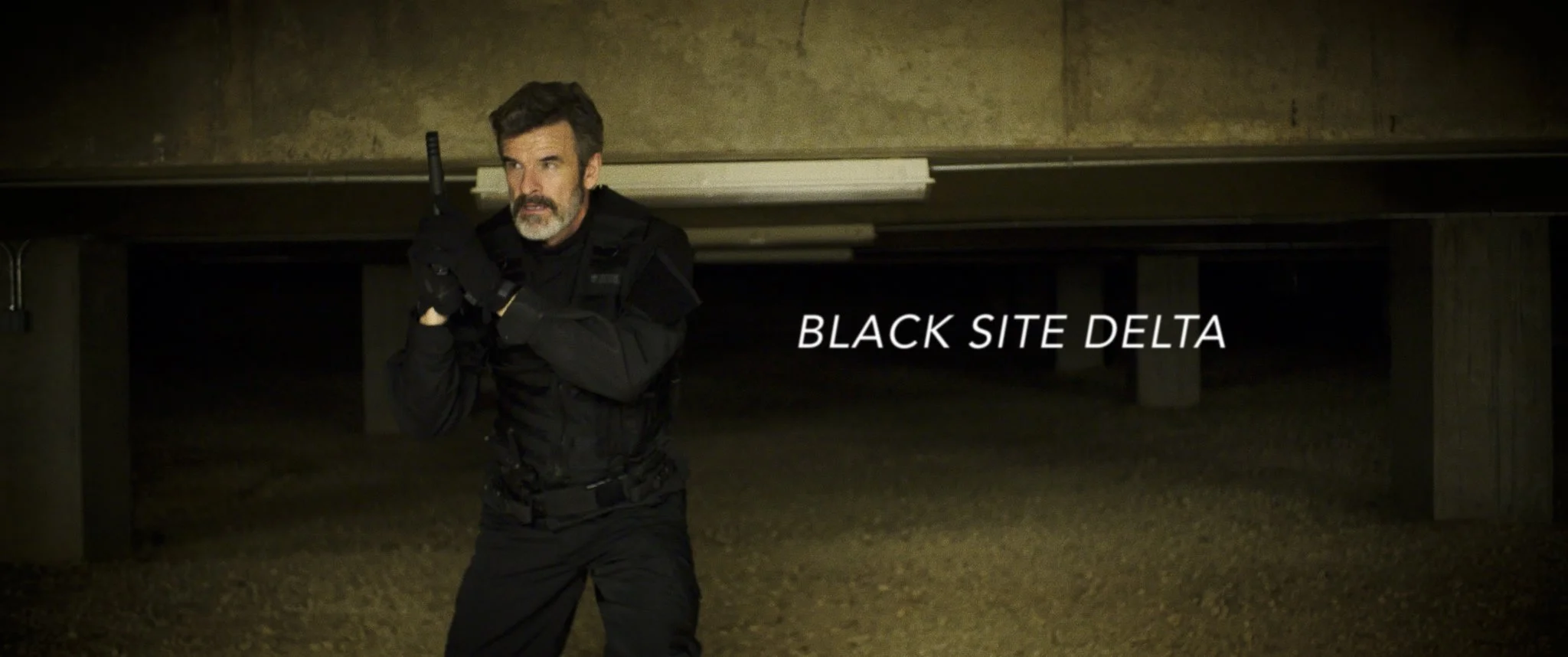 A man with a beard and dark hair dressed in black tactical gear crouches under a concrete structure, holding a firearm, with the text 'BLACK SITE DELTA' on the image.