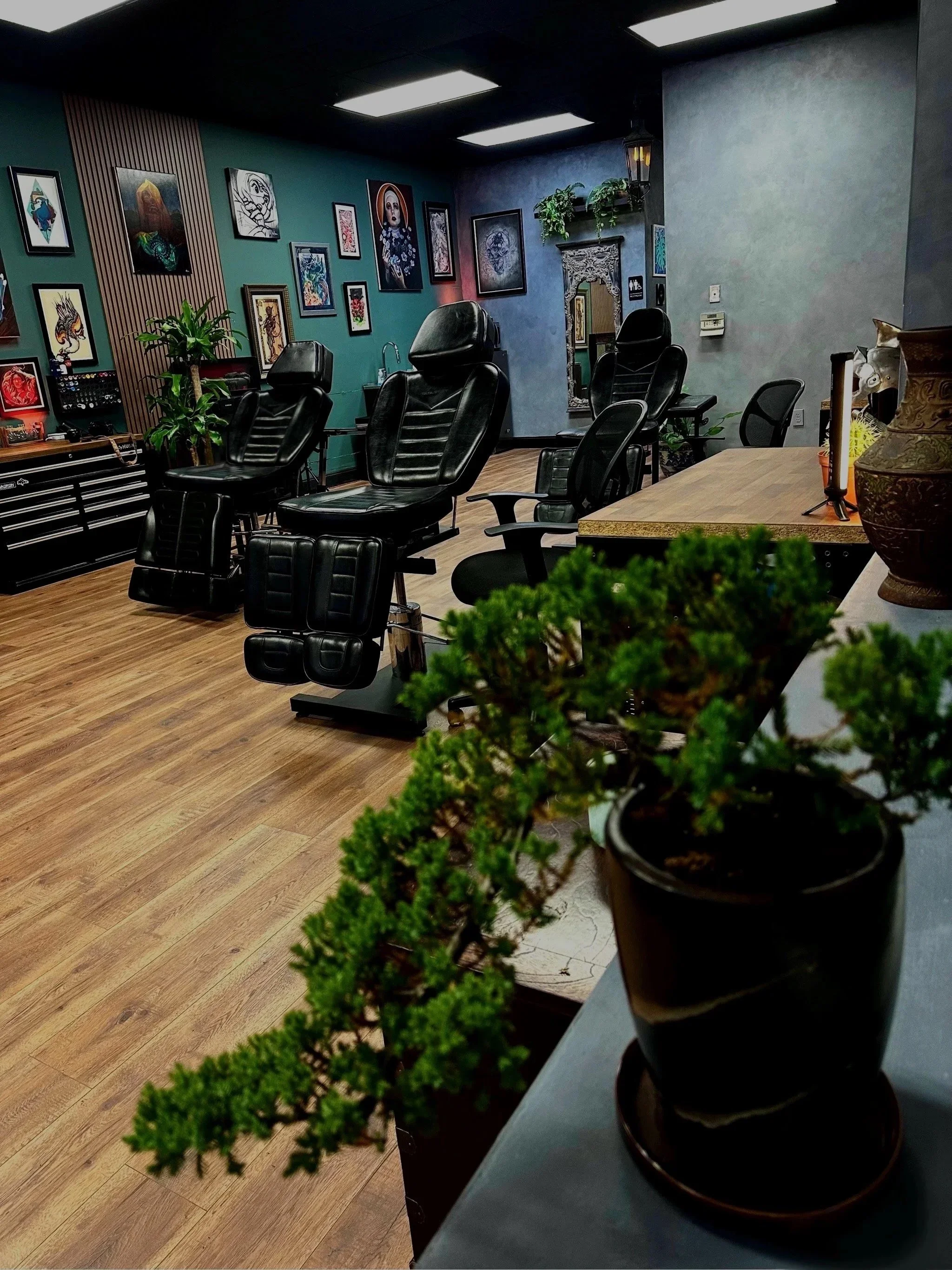 Black Craft Tattoo Collective interior with tattoo stations, framed art and plants in Charlotte, NC.