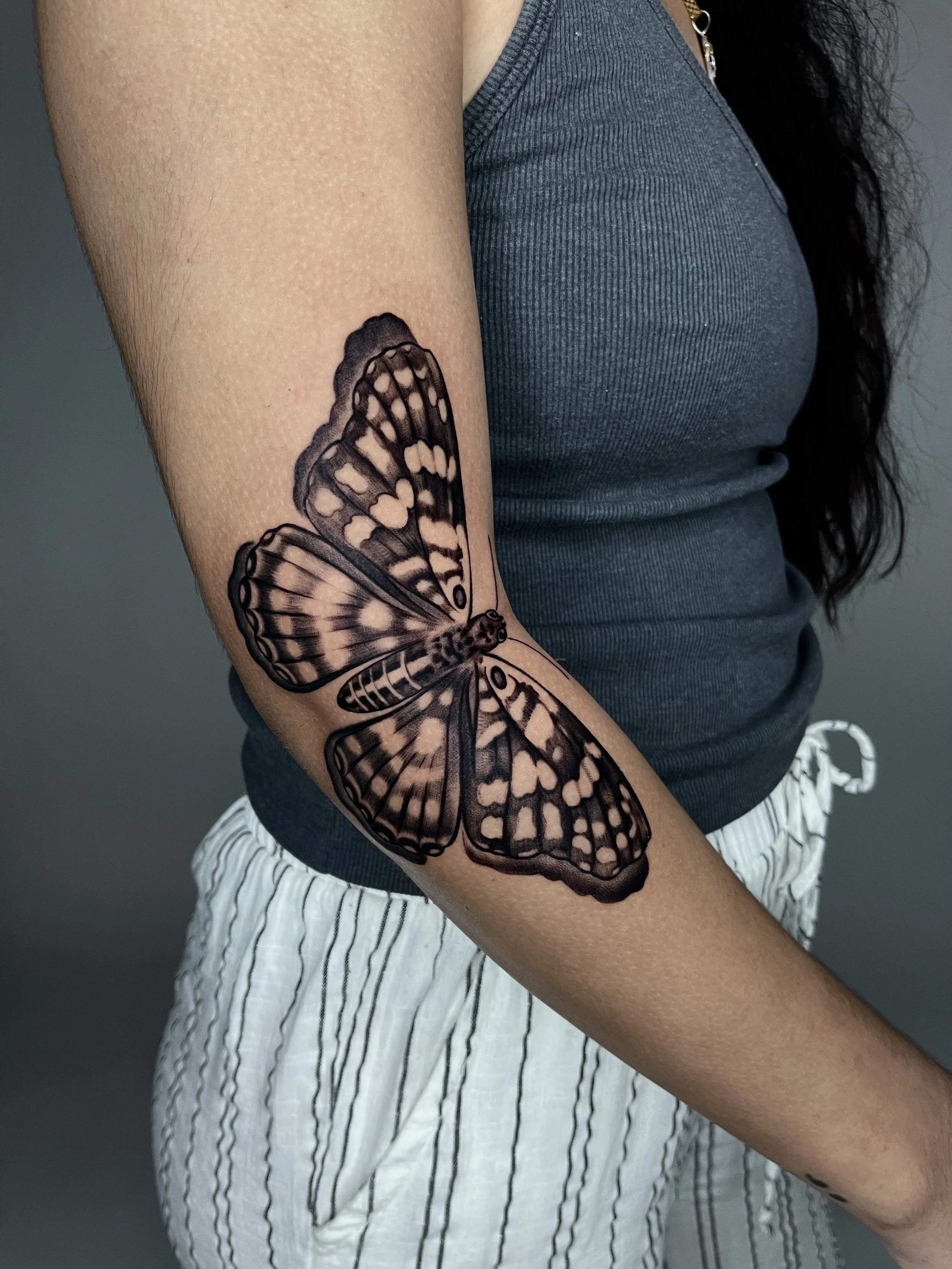 Black-and-gray butterfly arm tattoo at Black Craft Tattoo Collective in Charlotte, NC.